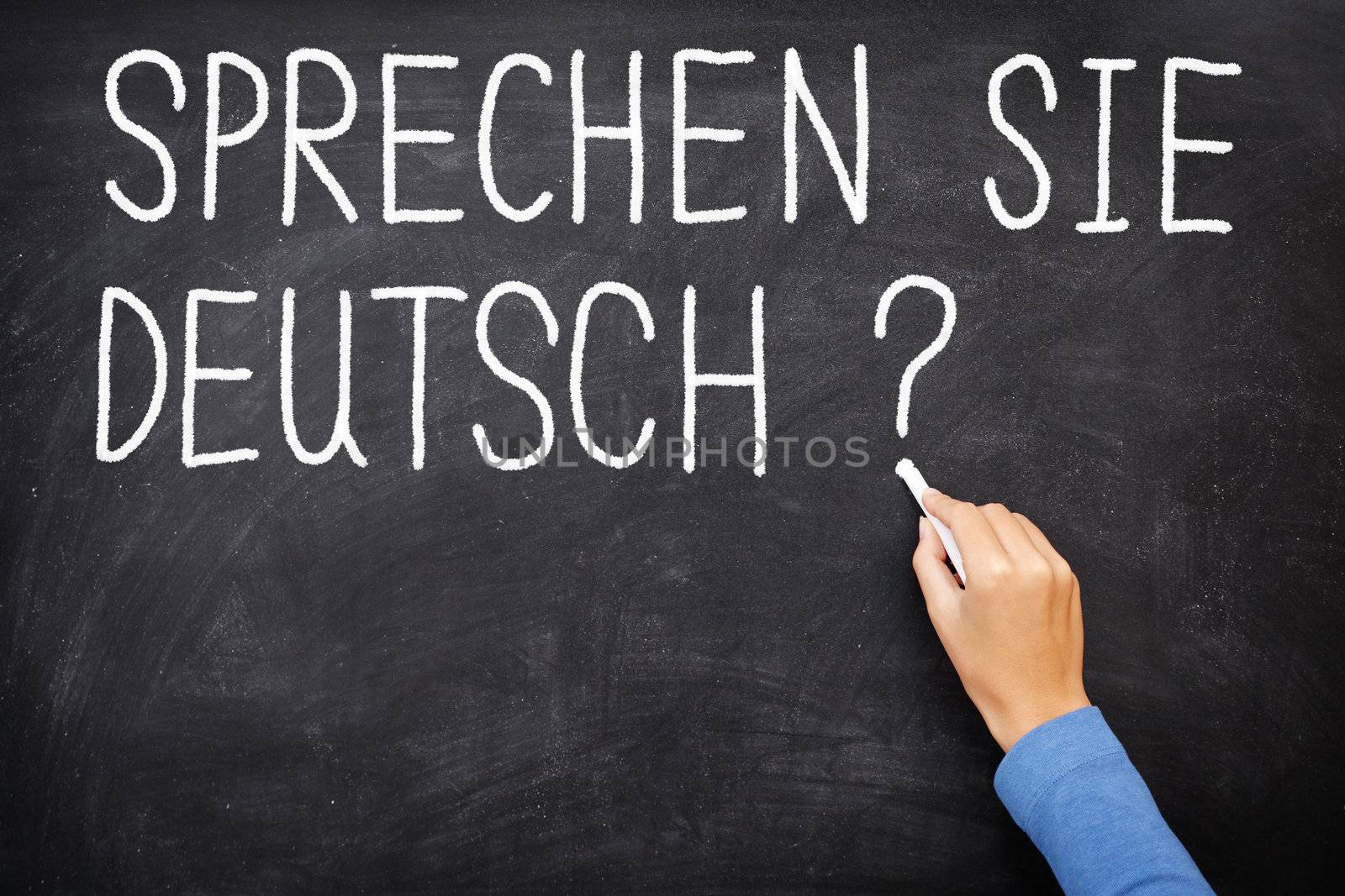 Learning language - German. Sprechen Sie Deutch (Do you speak German) written on blackboard. German language class concept showing teacher hand writing in German on chalkboard.