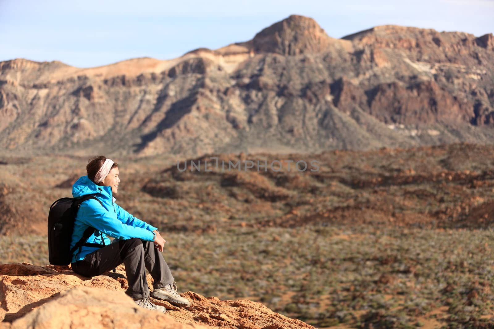 Hiking - woman hiker enjoying view. Woman sitting looking over beautiful volcano mountain landscape. From volcano Teide, Tenerife, Canary Islands, Spain.