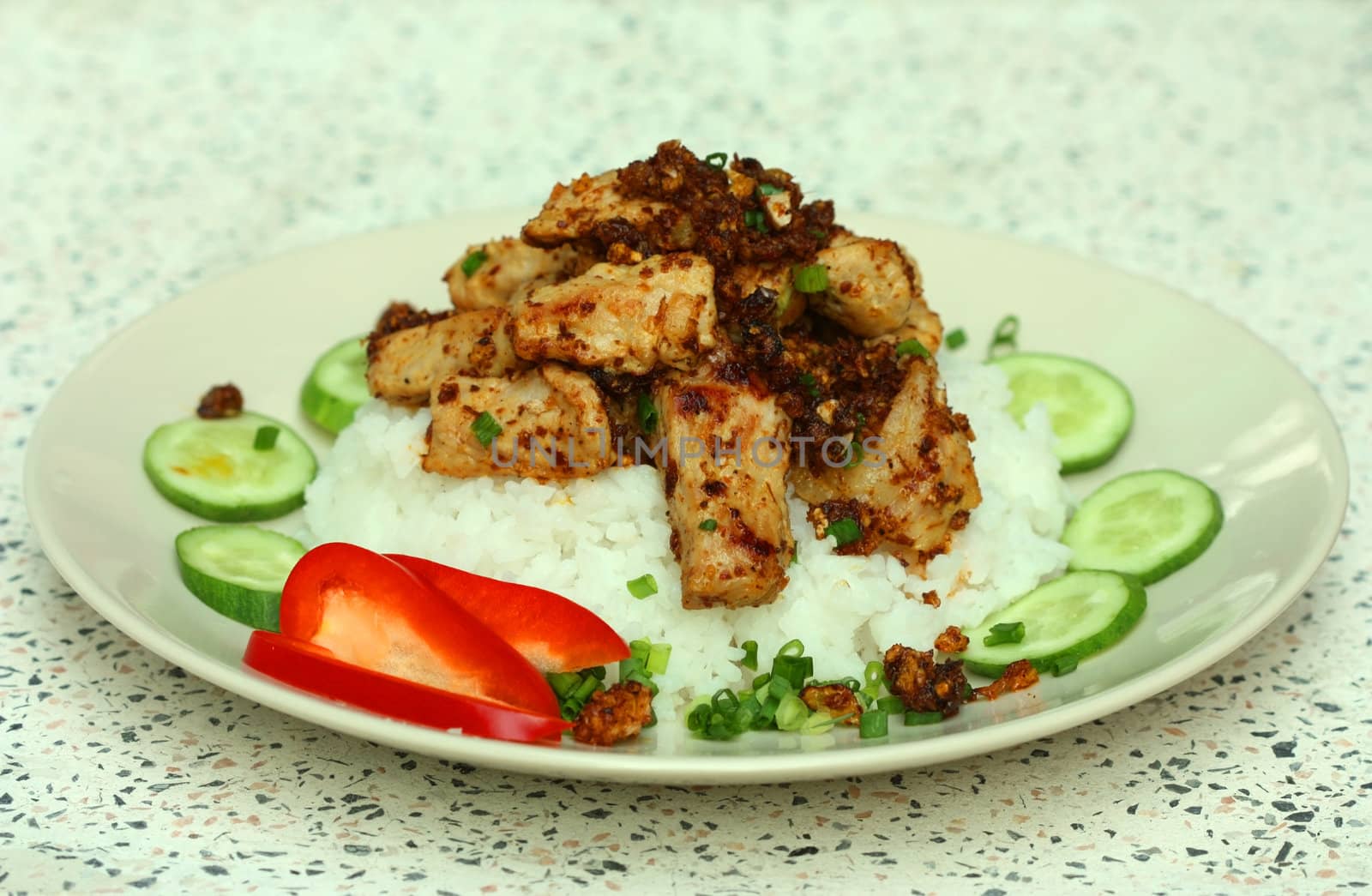 a dish of meat and rice, decorated with pepper and cucumber