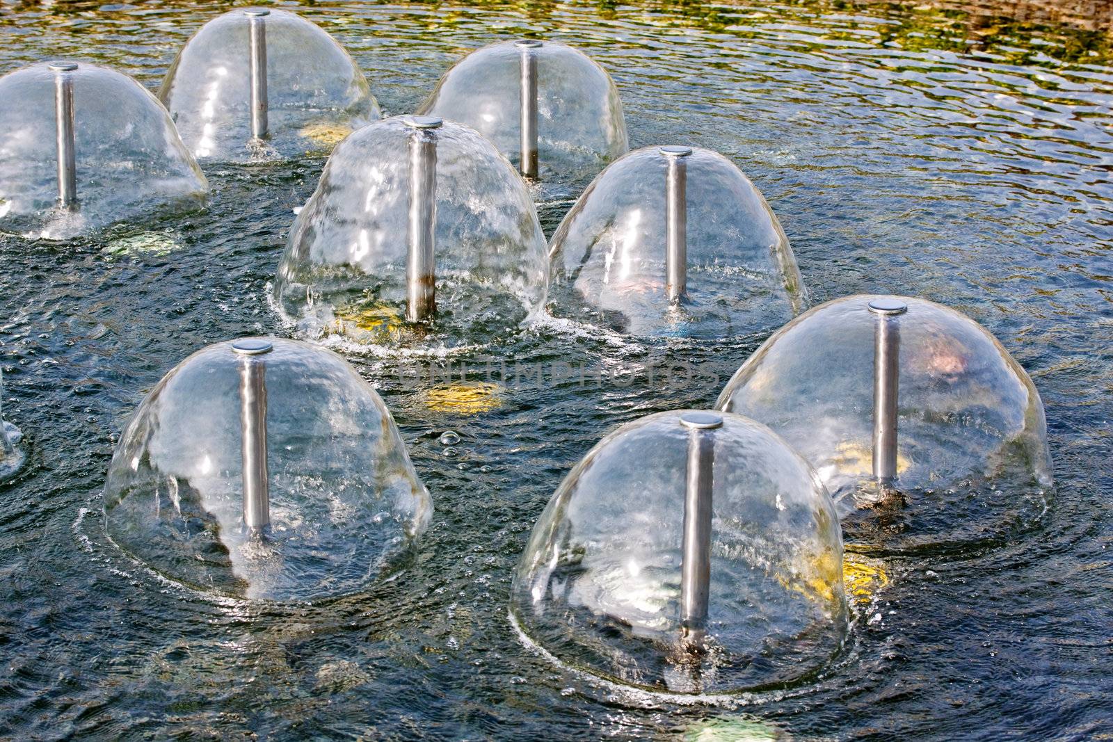 A group of small sperical fountains on a water in a sunny day