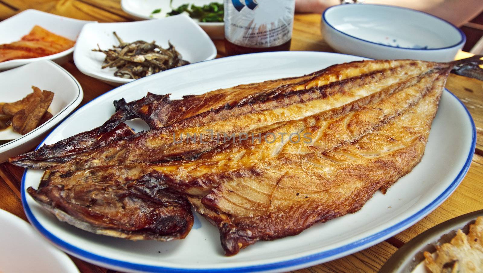 Korean style grilled fish on a table with snacks