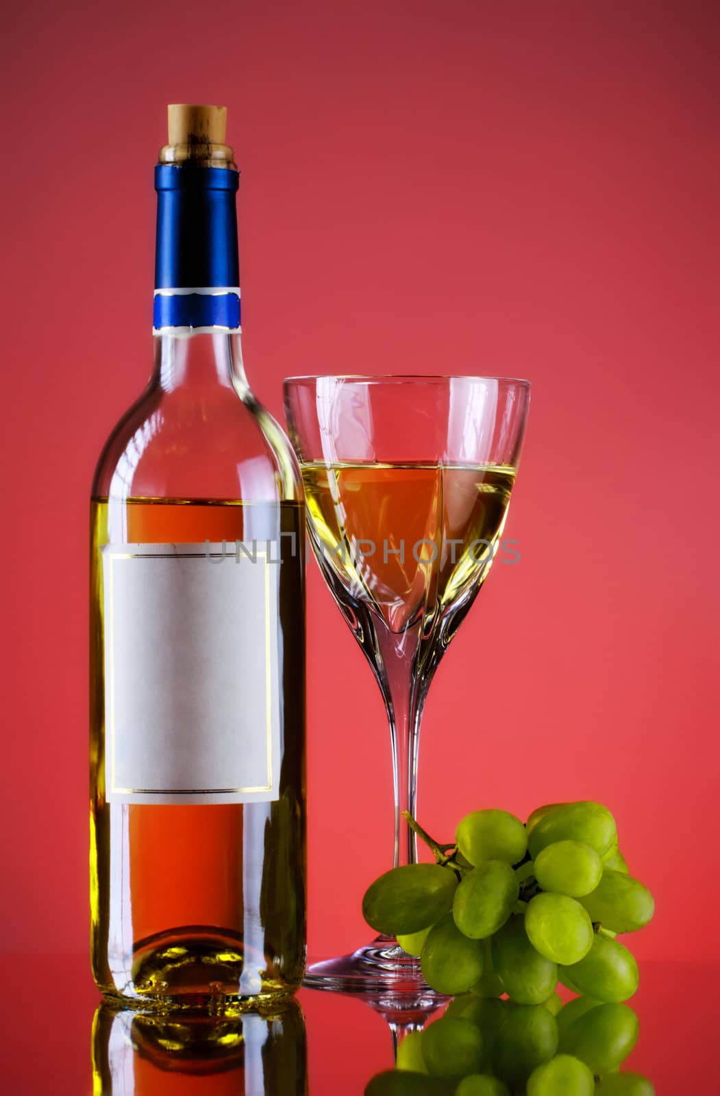 bottle and glass of wine, grape bunch, red background