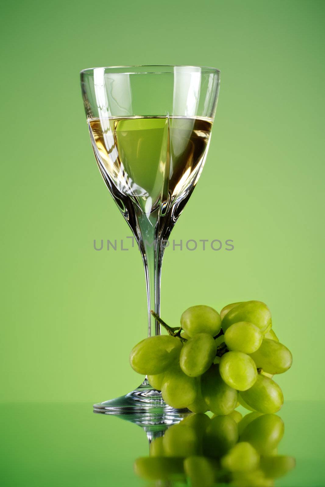 glass of wine and grape bunch, green background