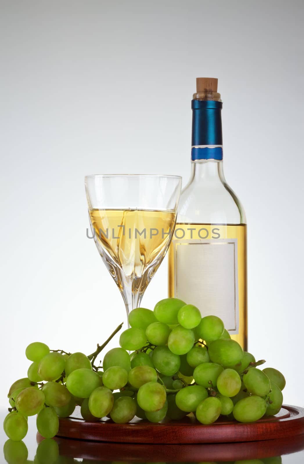 bottle and glass of wine, grape bunch, gray background