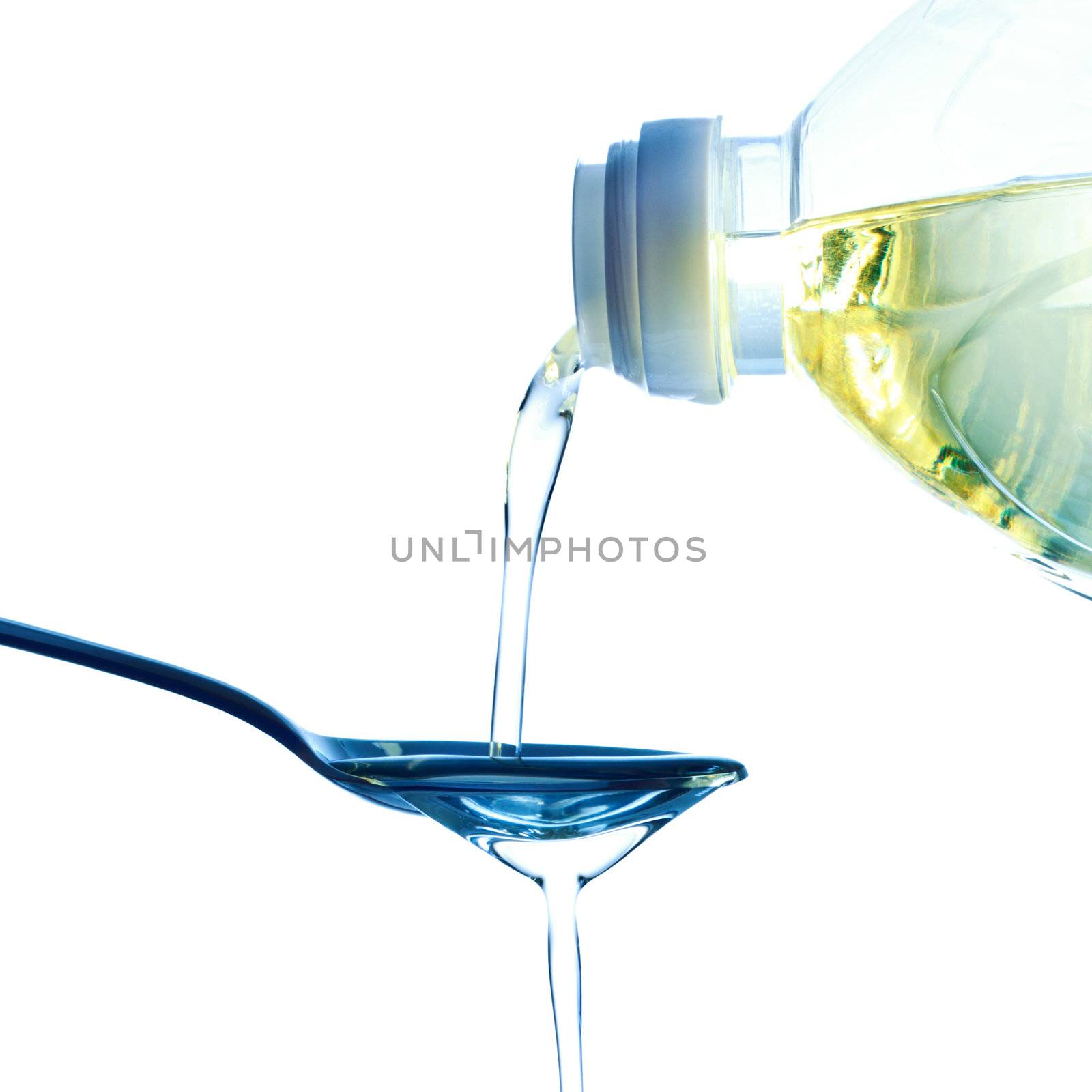 pouring olive oil on spoon, white background