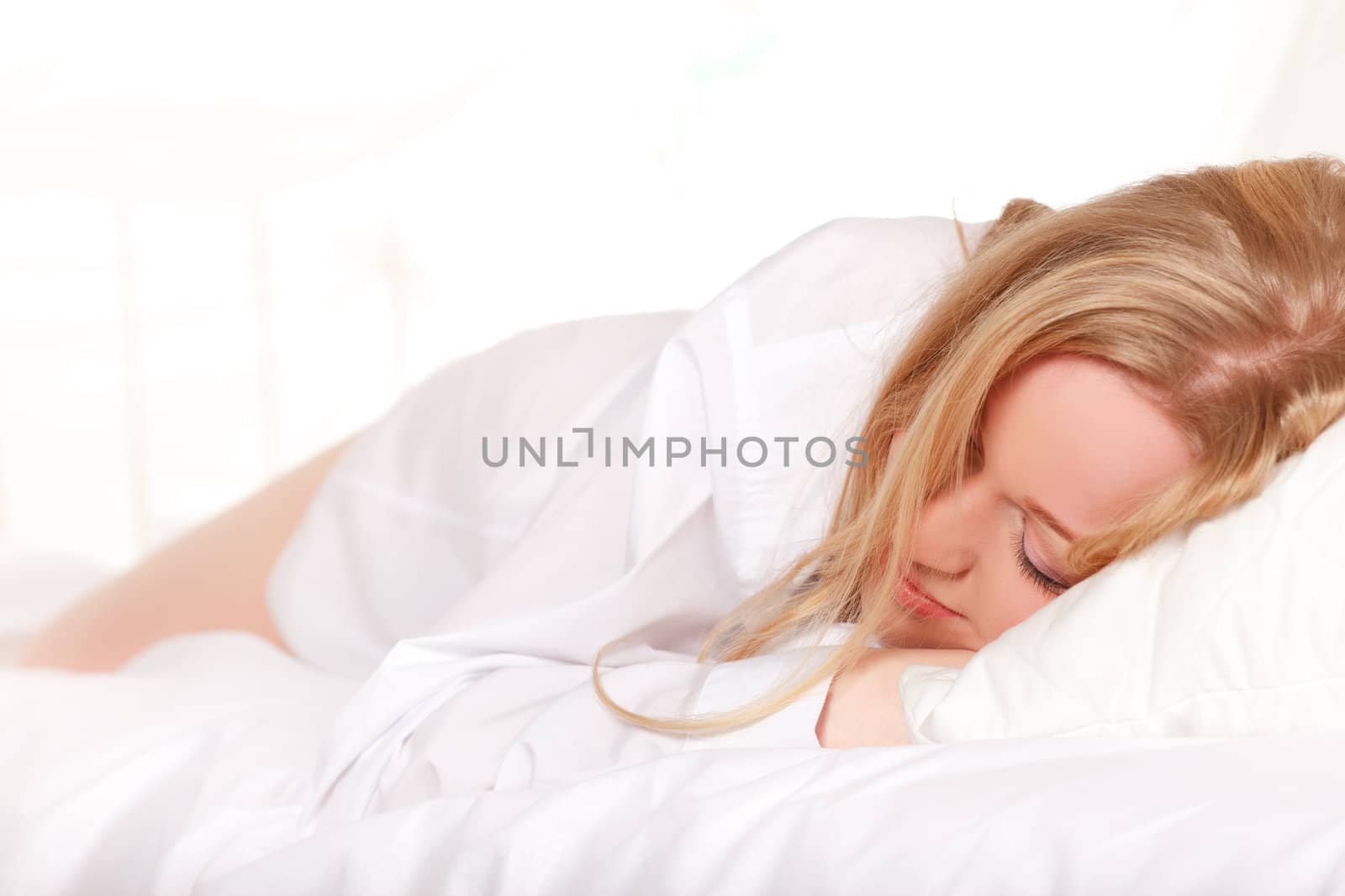 sleeping blonde woman in bed at morning