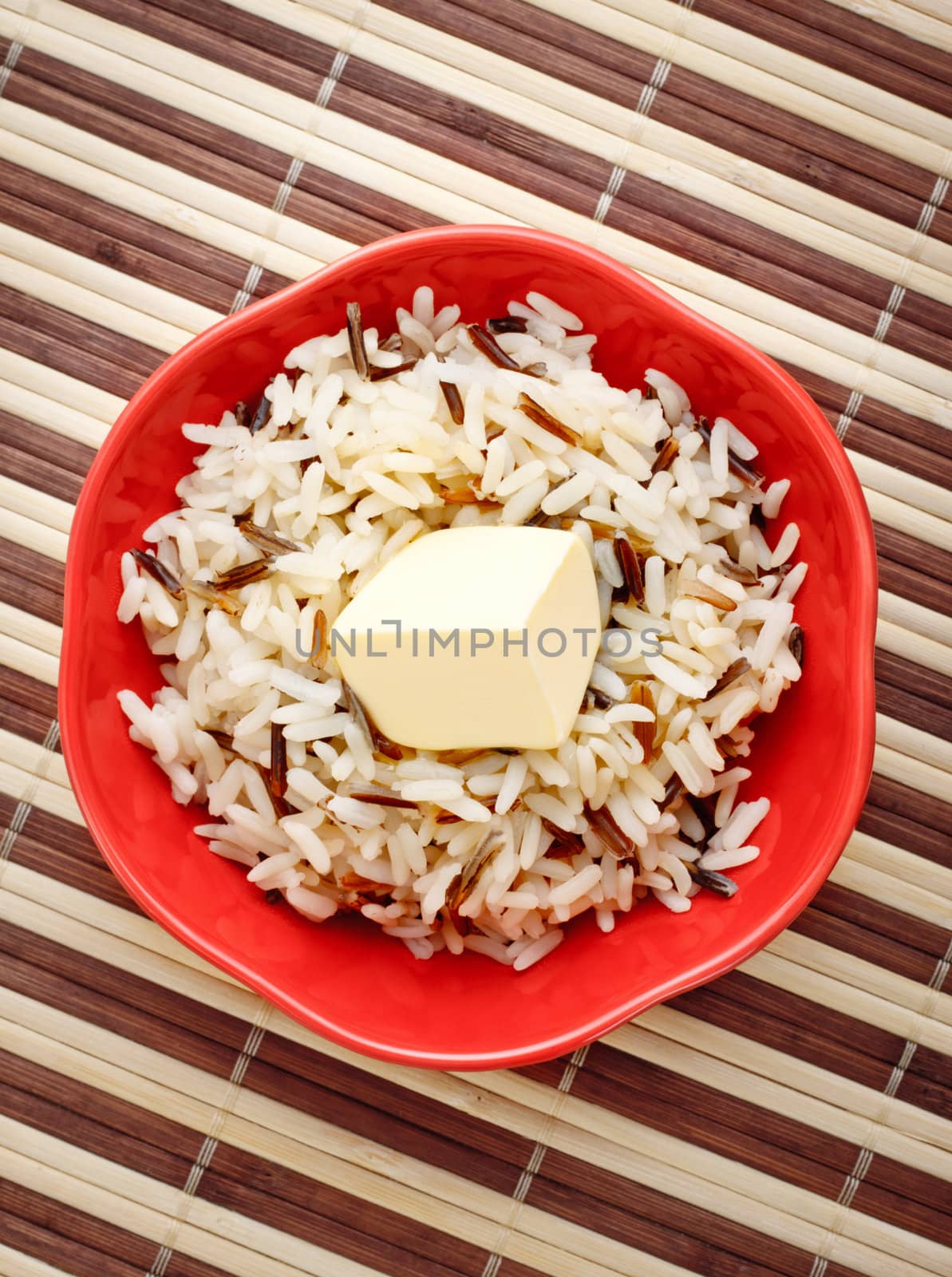 red bowl with cooked rice and butter on bamboo napkin