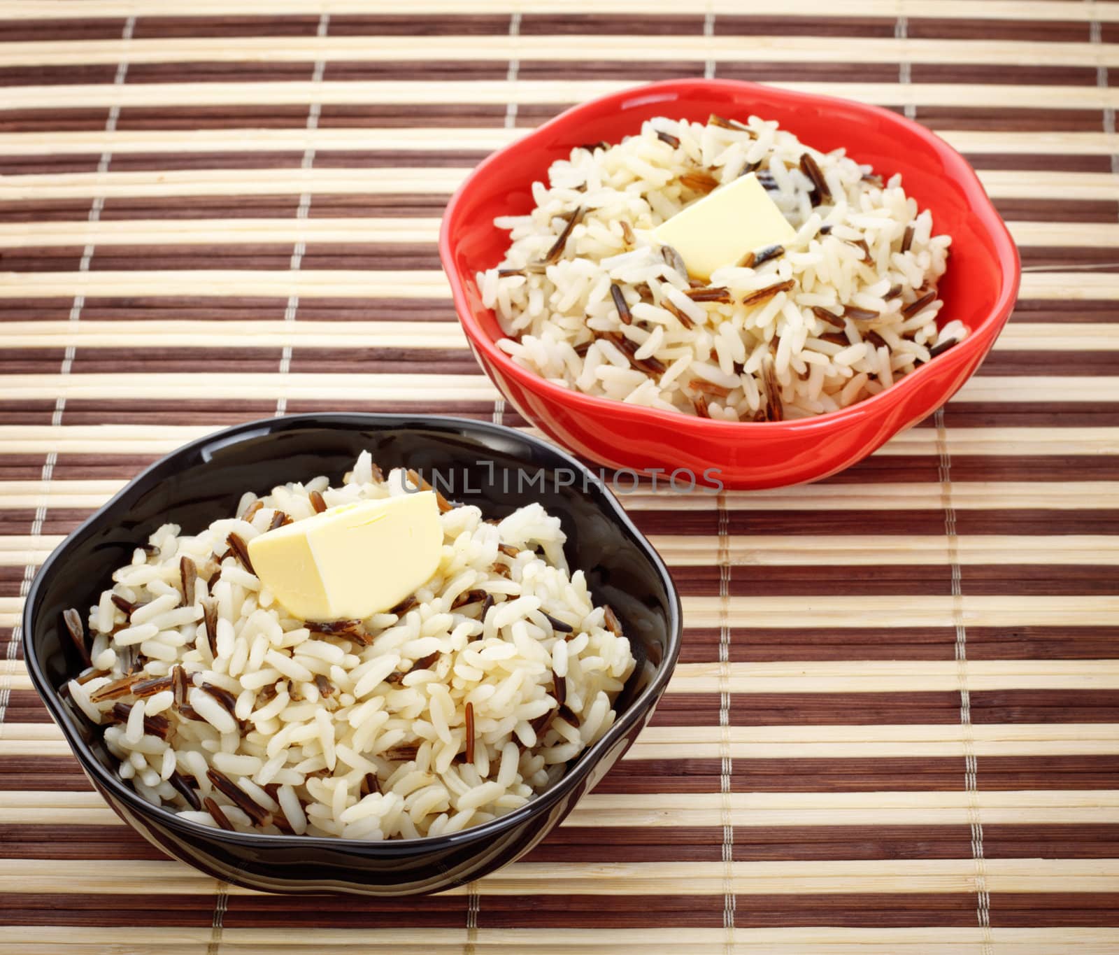 two bowls with cooked rice and butter on bamboo napkin