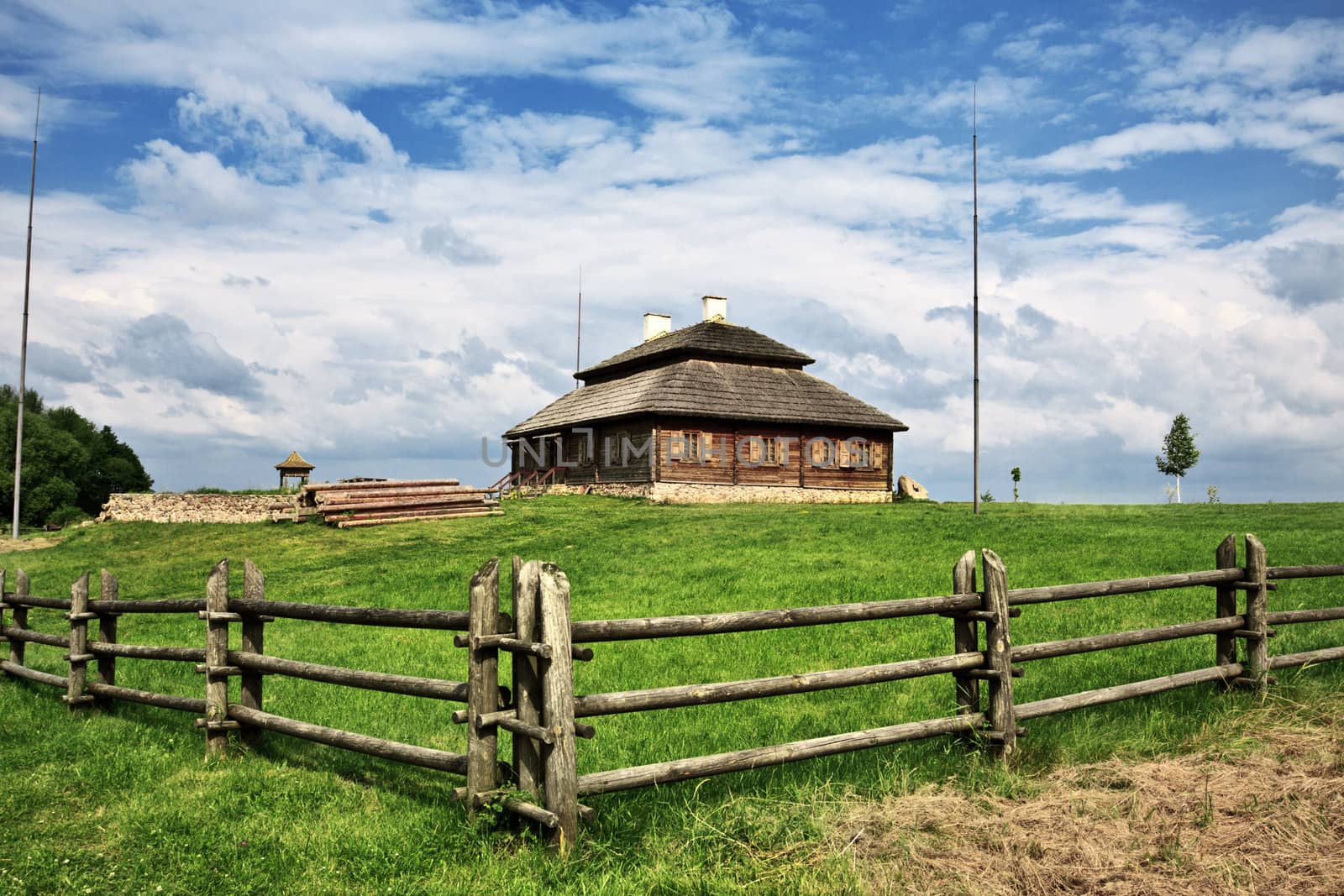 wooden cottage on green hill under cloudy sky