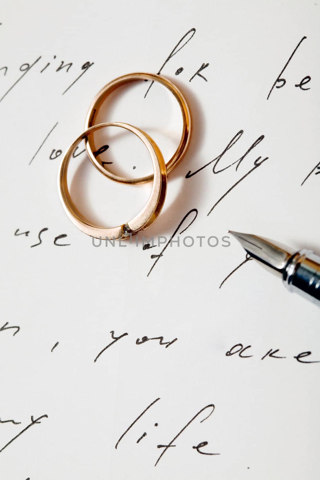 An image of two golden rings on a letter and a pen
