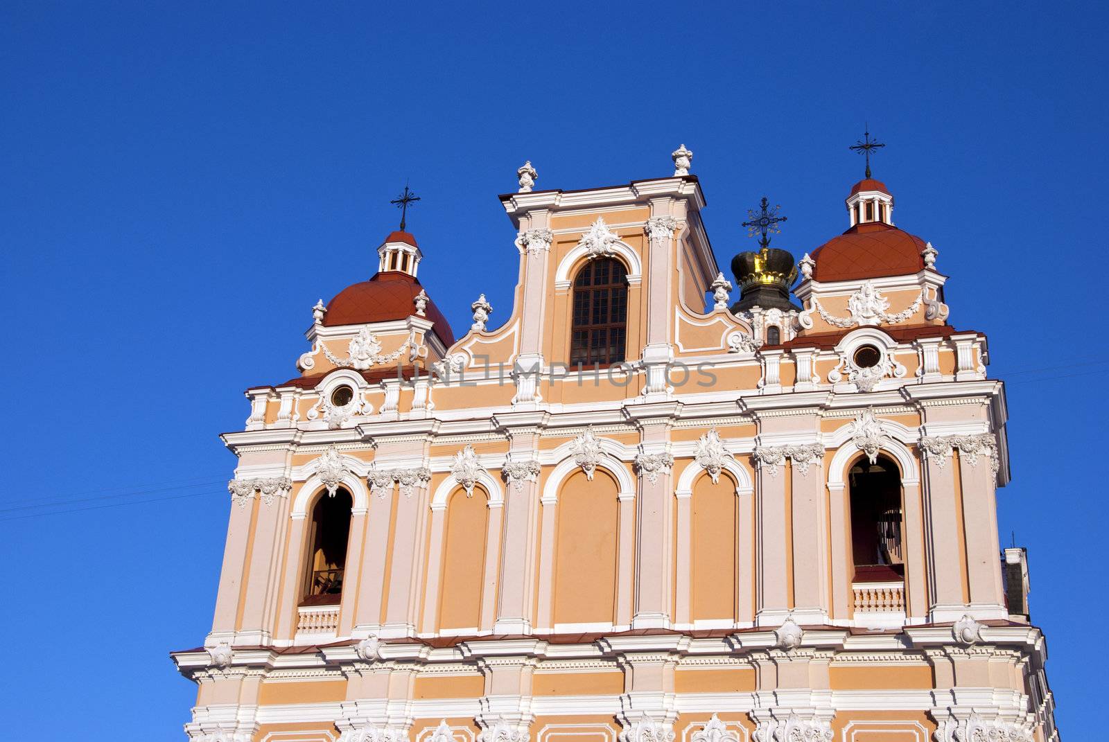 Religious building wall and towers cross church in Vilnius on background of blue sky.