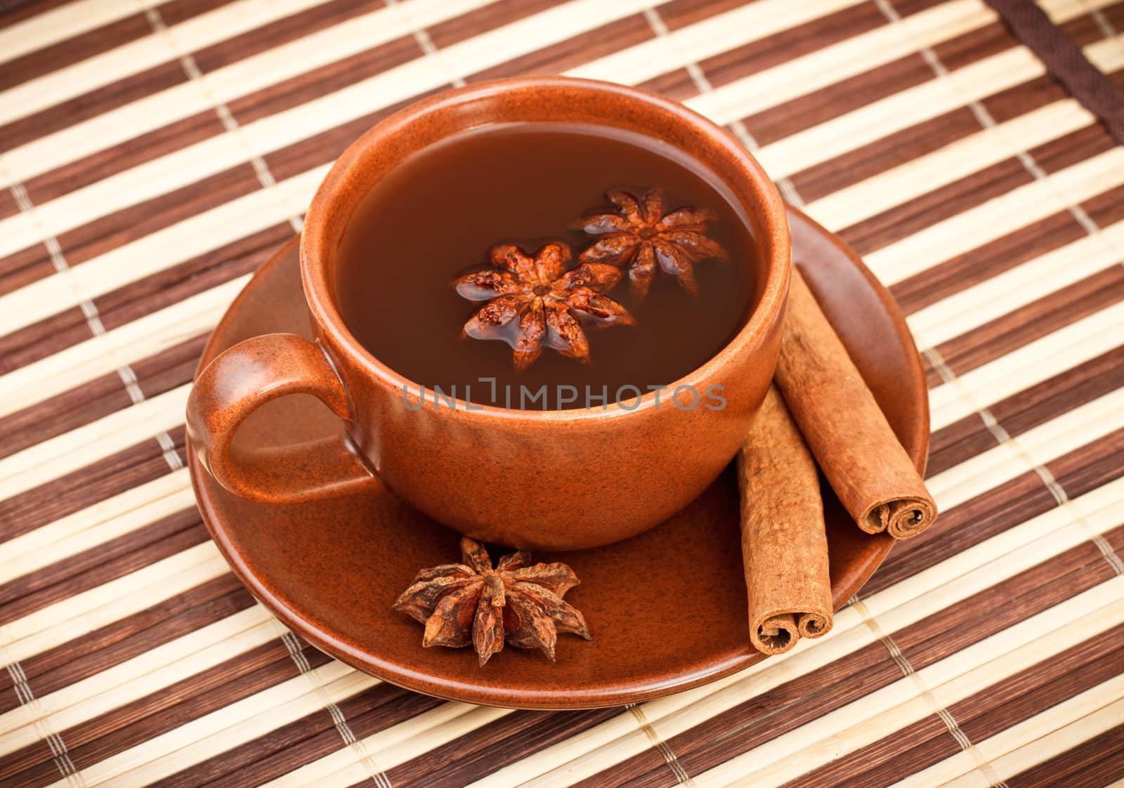 cup of winter tea with cinnamon and star anise on bamboo napkin