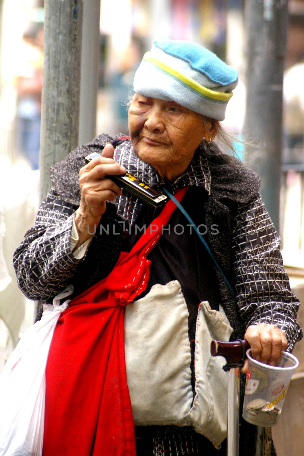 Old woman playing music along the street in Hong Kong by kawing921