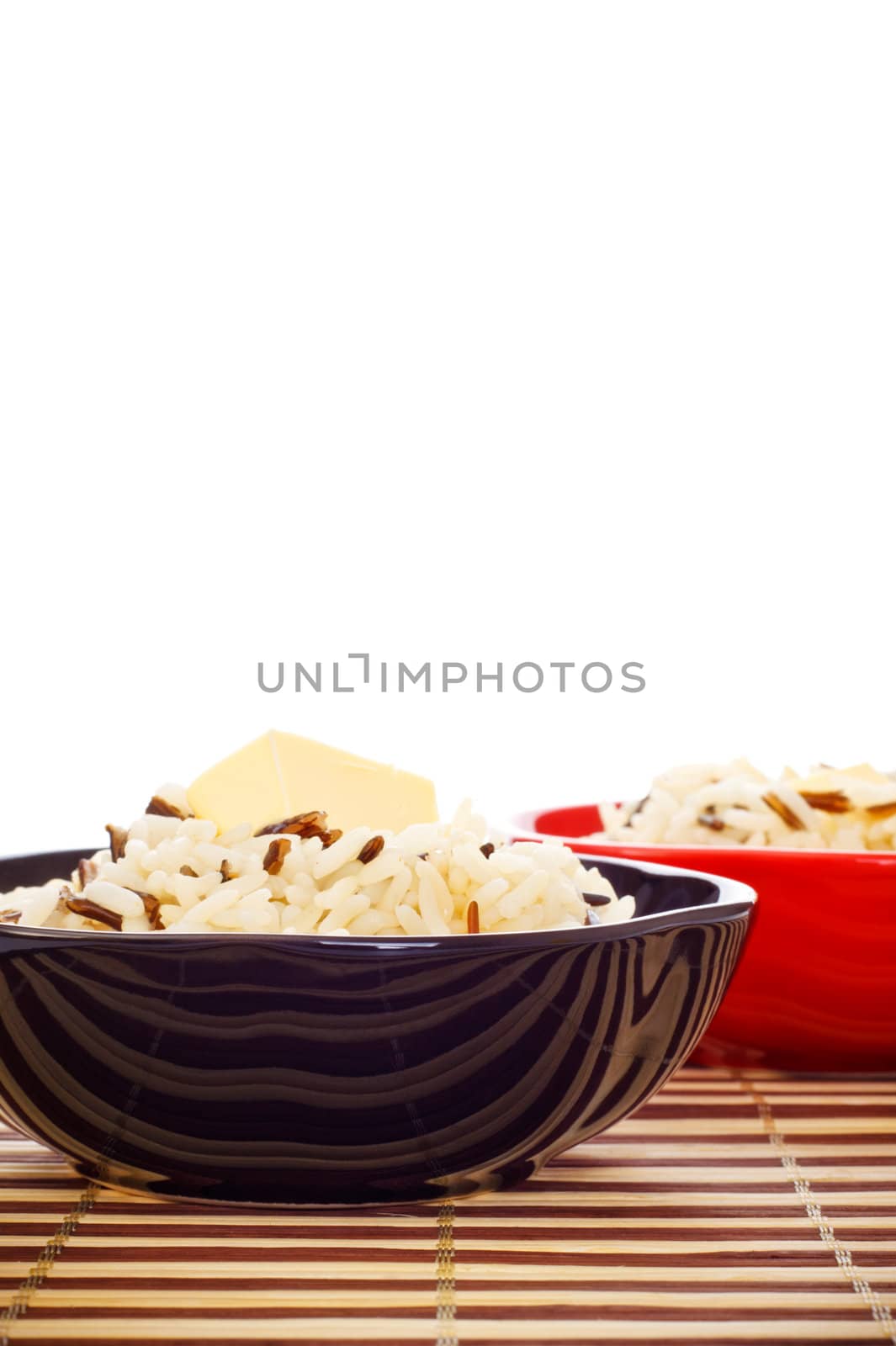 bowls with cooked rice and butter on bamboo napkin