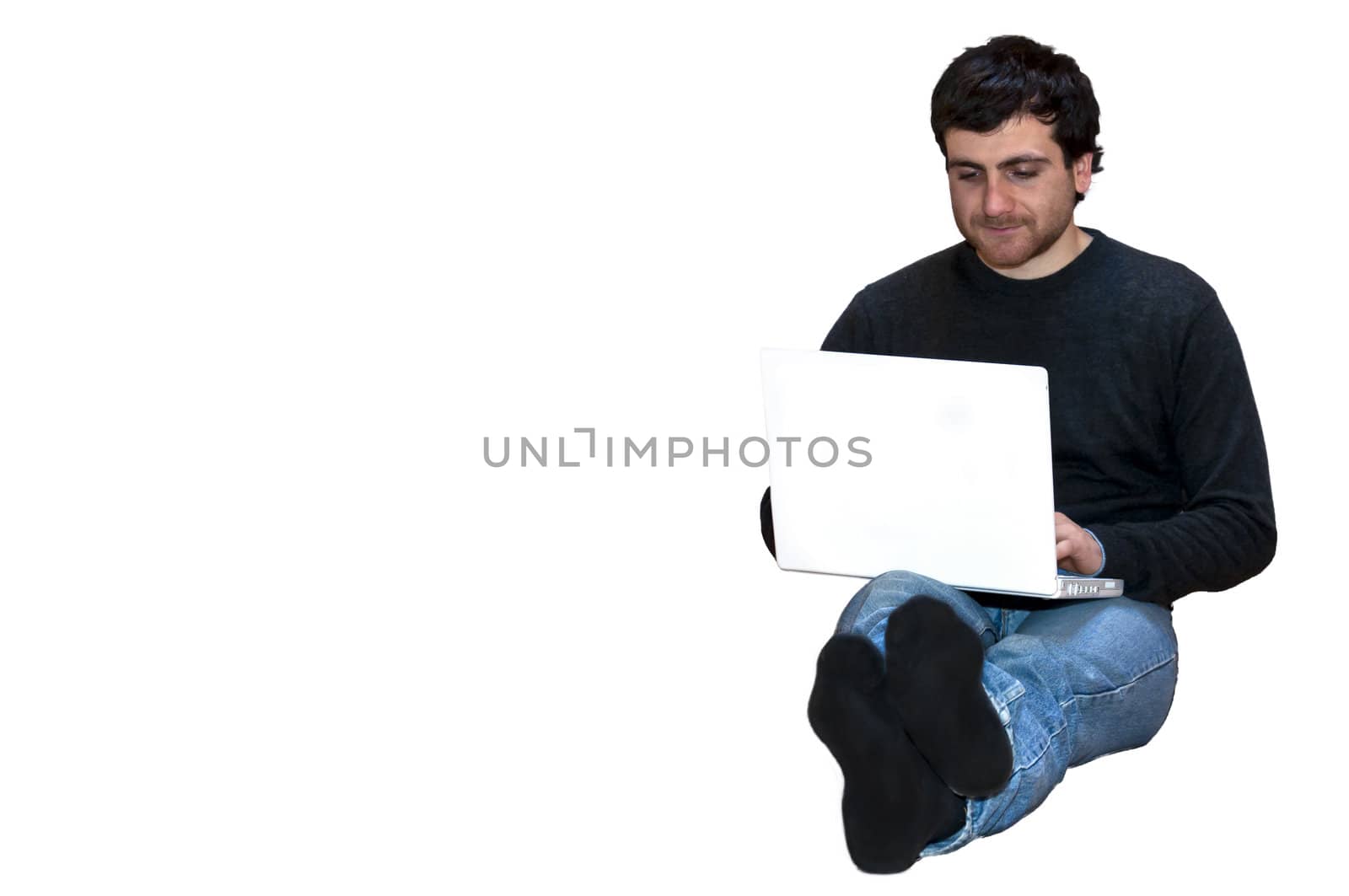 young man sitting on the floor cross-legged with laptop.