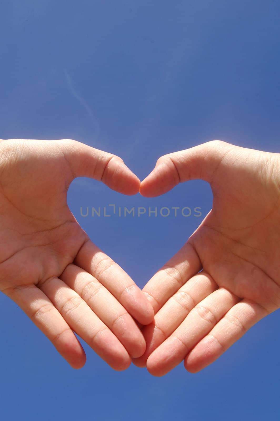 Man hands forming a heart over the blue sky 