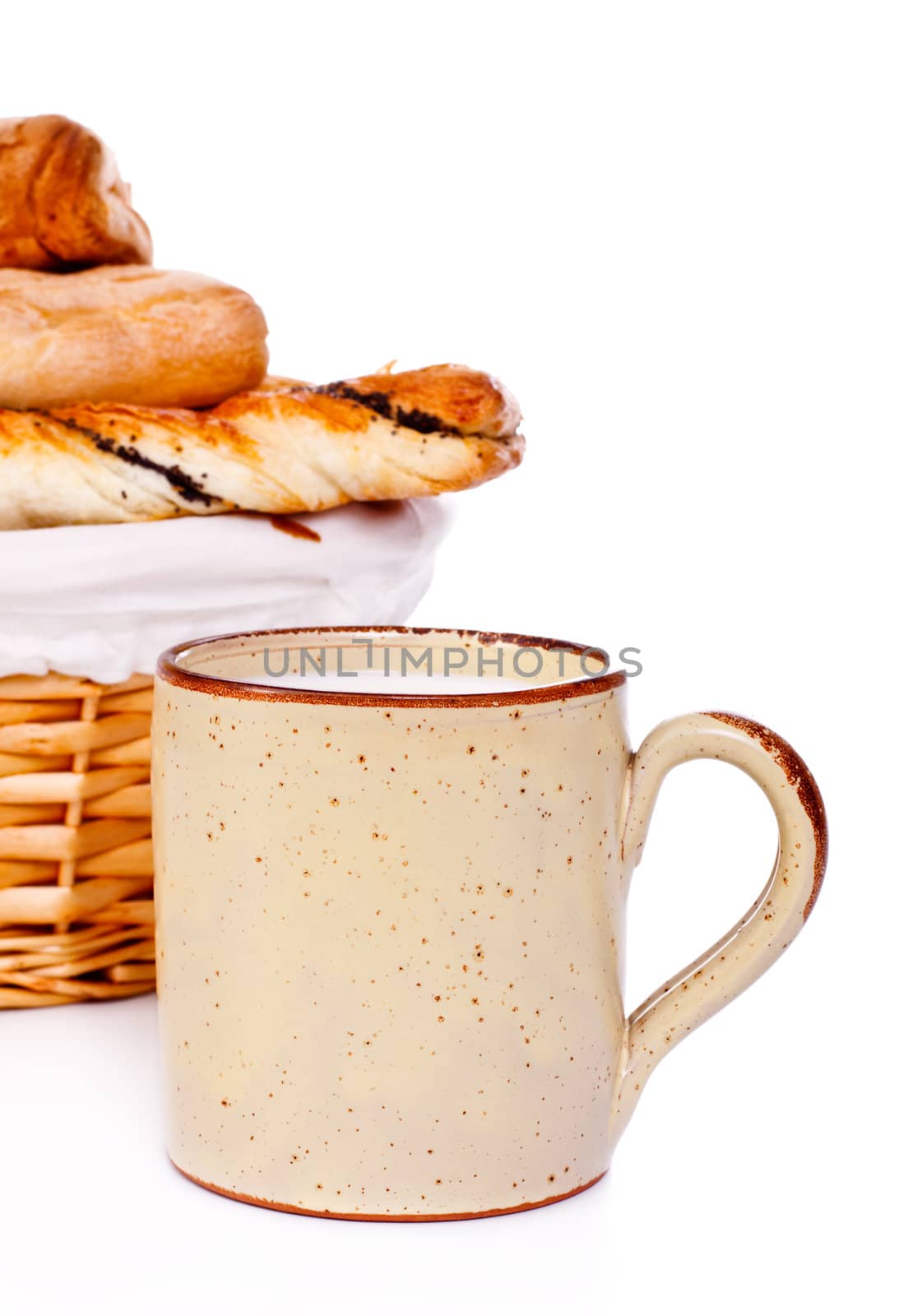 basket with buns and mug of milk on white
