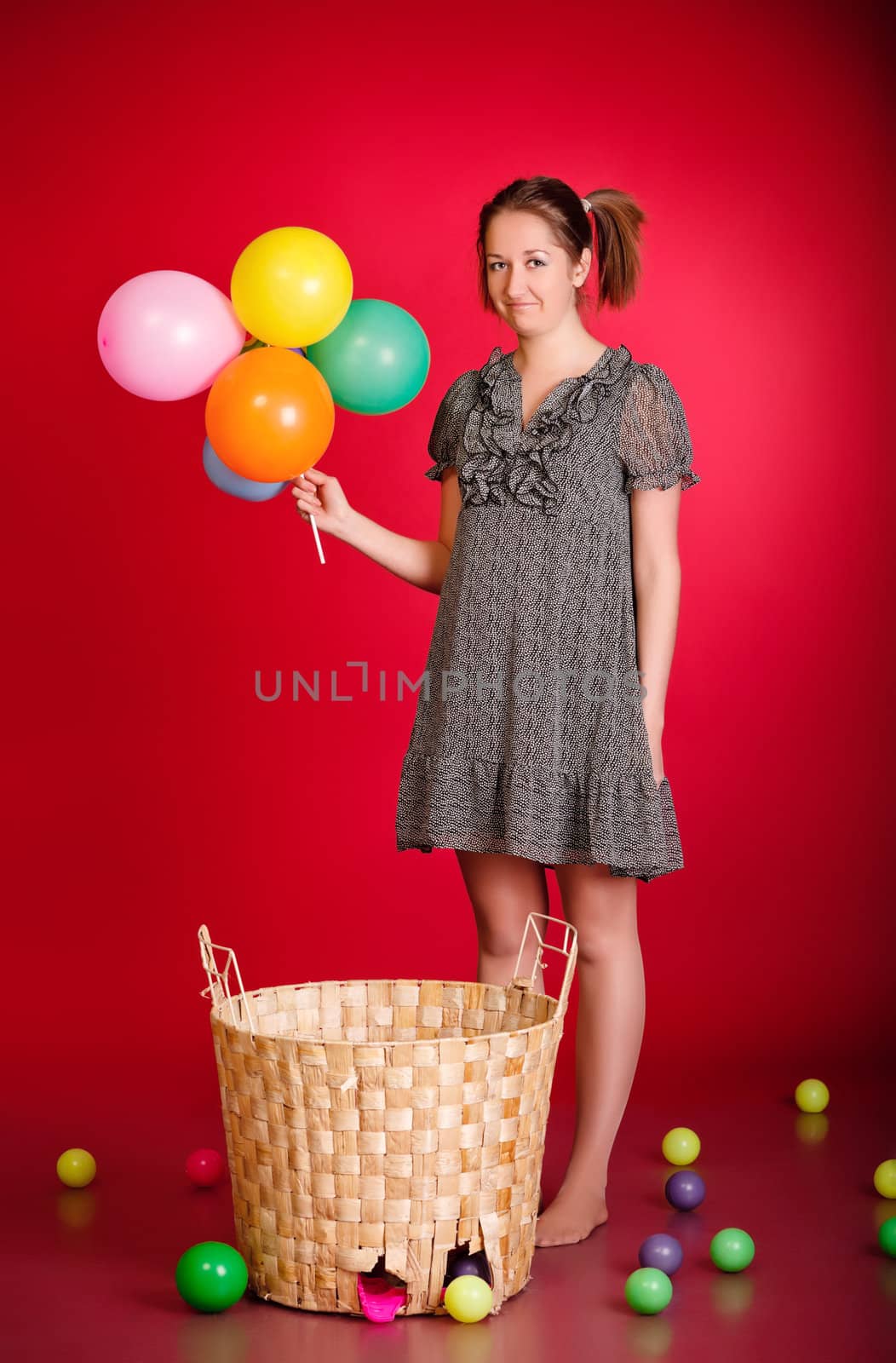 funny girl with toys and balloons, red background