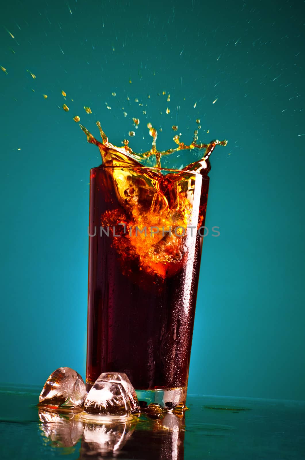 glass with splashing cola on blue background