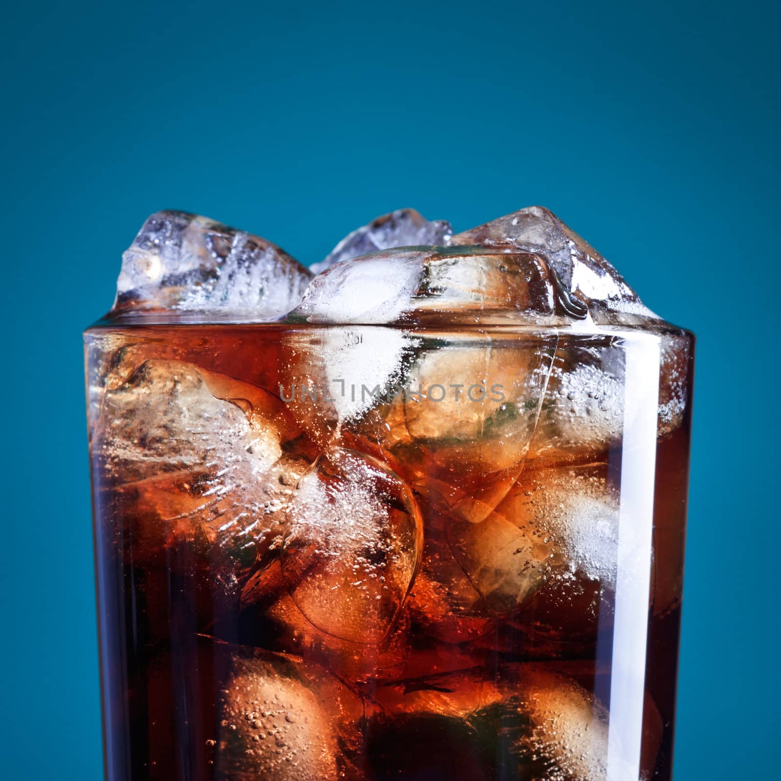 glass of cola with ice on blue background