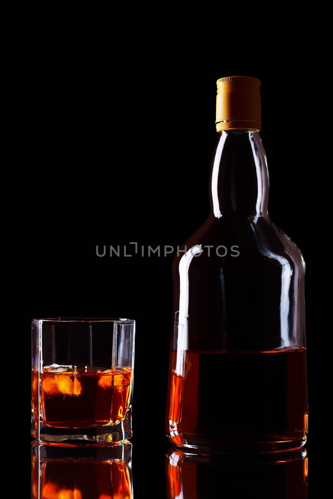 bottle and glass of whiskey on black background