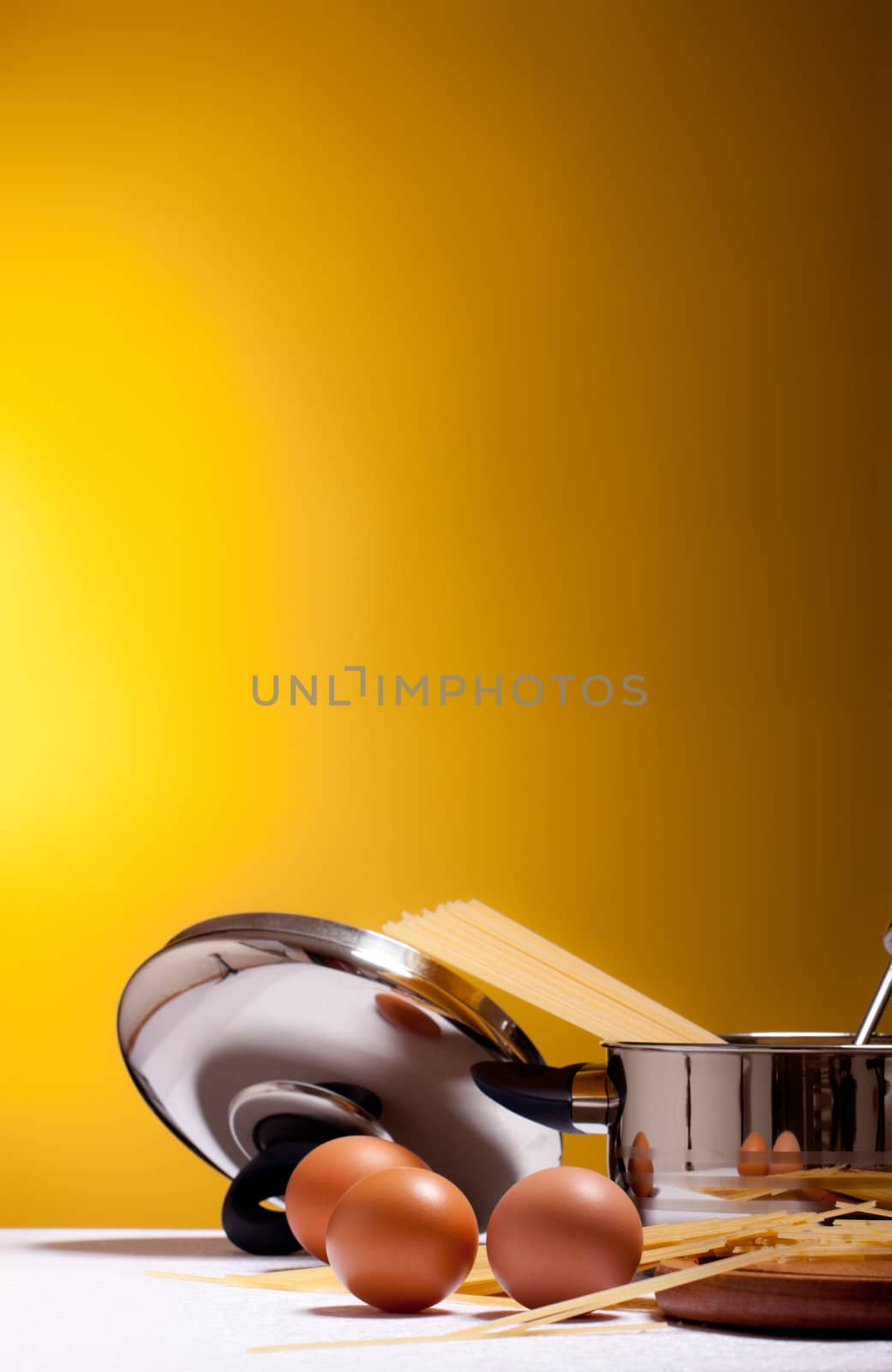 spaghetti, eggs, cheese and utensils on table