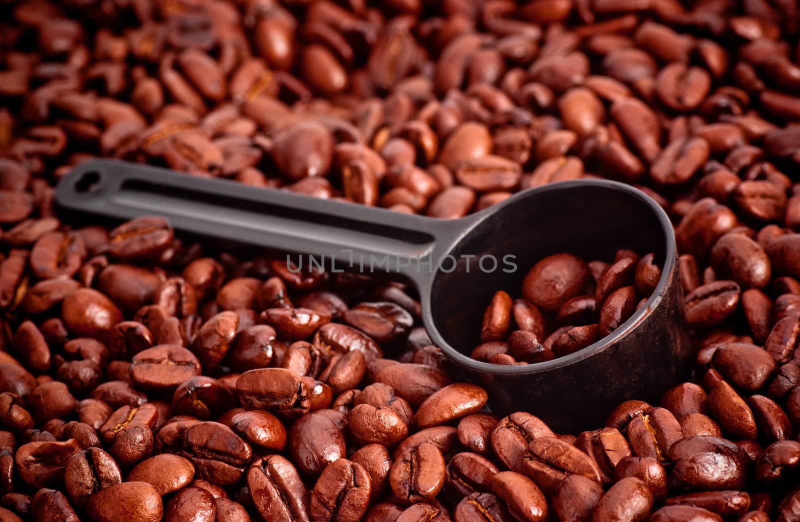 coffee beans and measuring spoon against white background