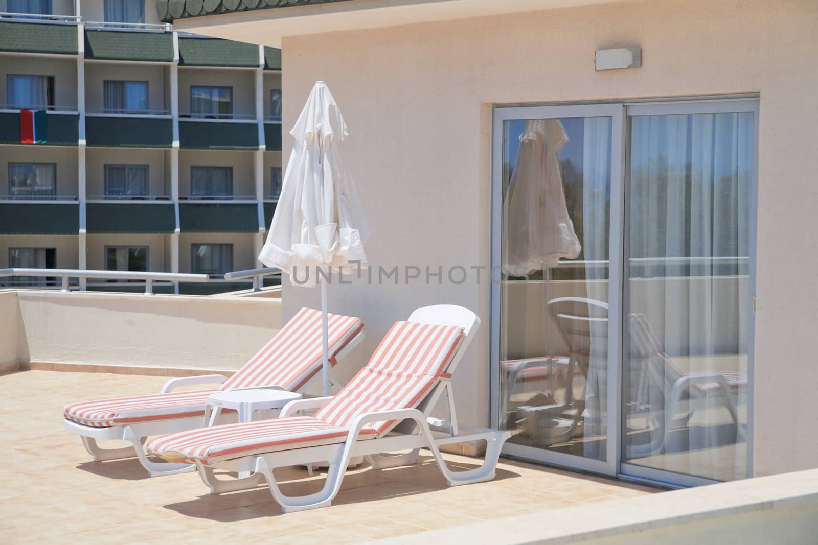 Umbrella and chaise lounges on a balcony of apartments of luxury hotel