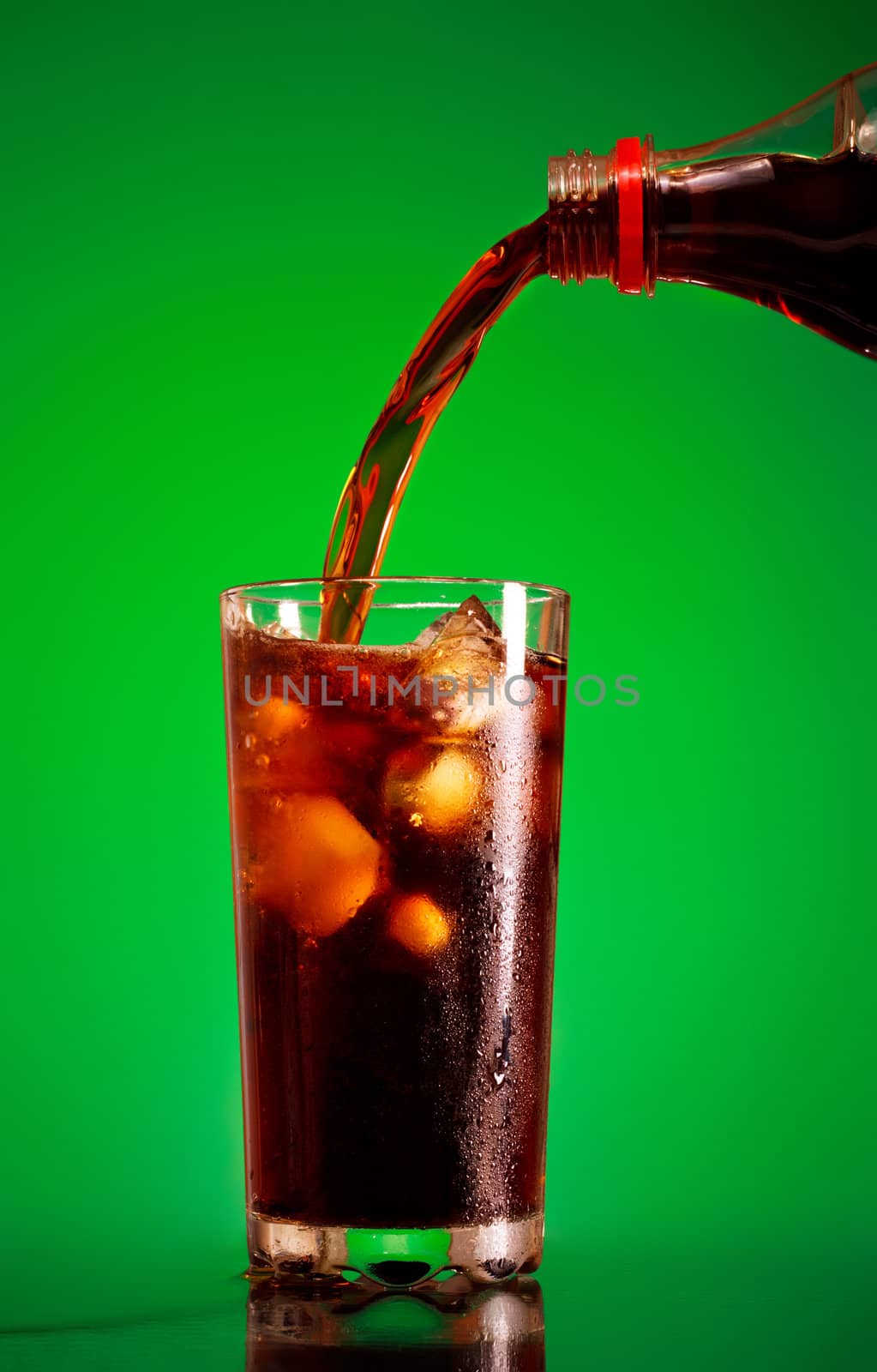 pouring cola in glass over green background