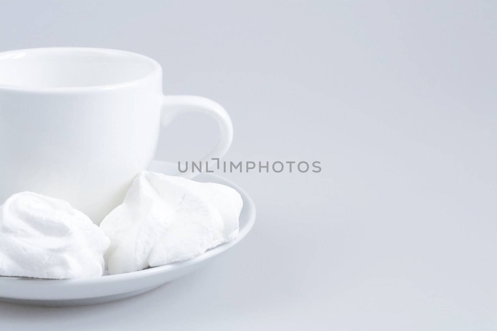 White ceramic cup and cakes on a light gray background