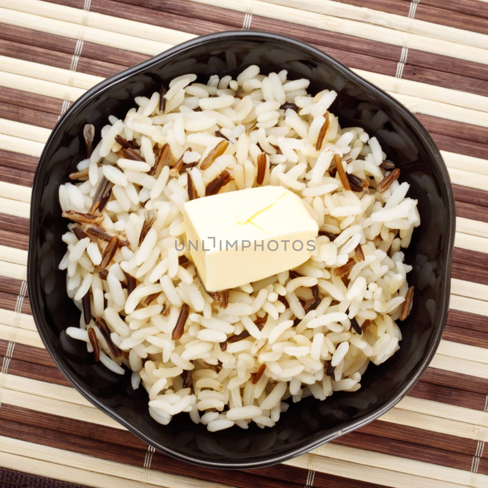 black bowl with cooked rice and butter on bamboo napkin