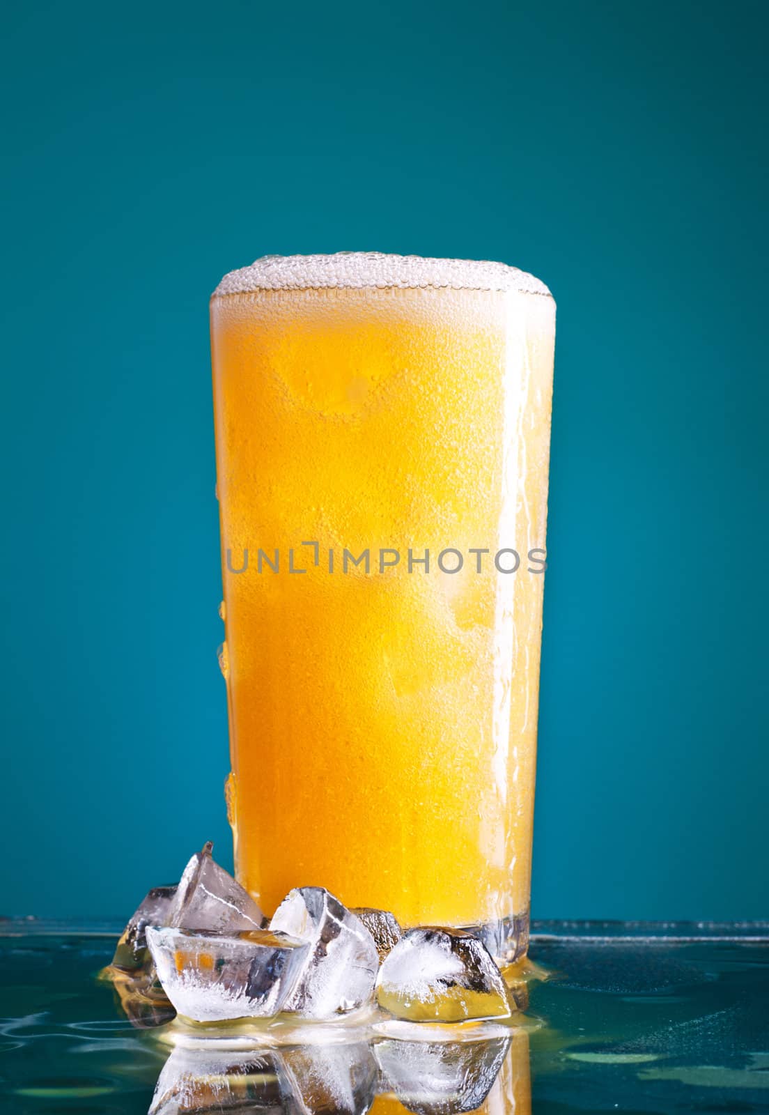 glass of orange soda with ice over blue background