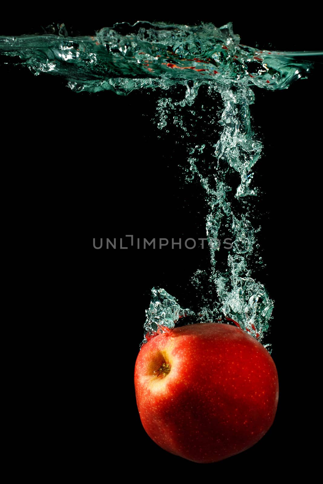 apple falling to water with splash over black background