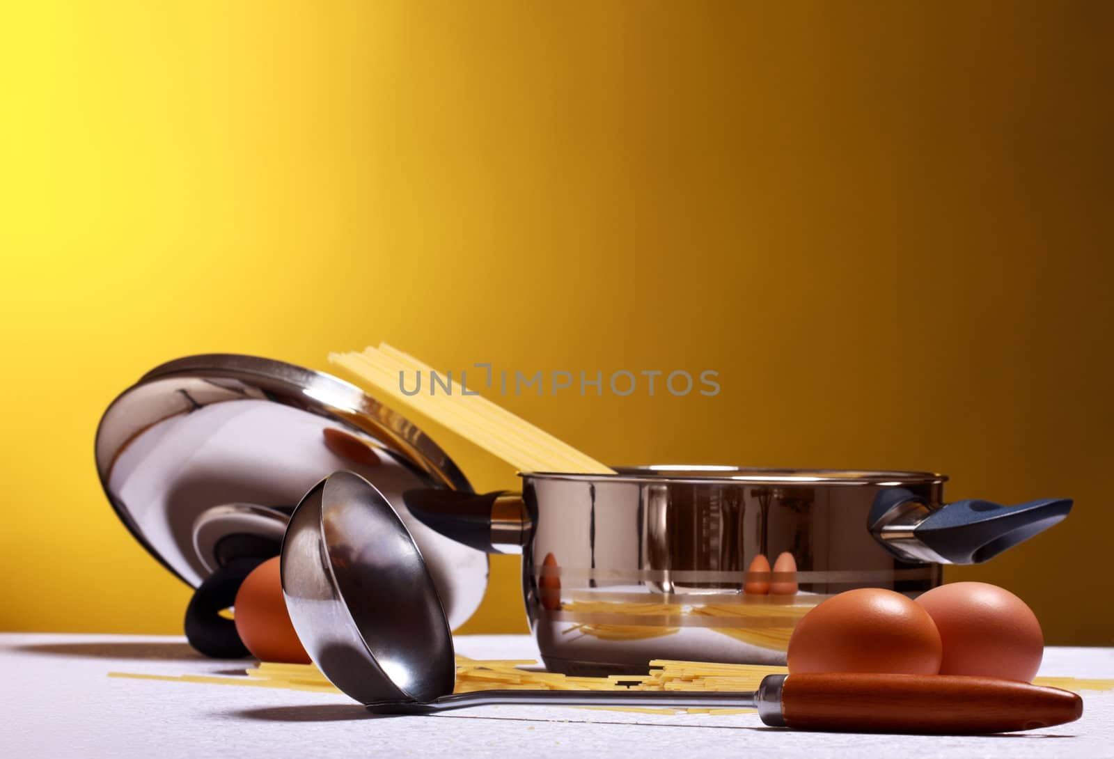 spaghetti, eggs, cheese and utensils on table