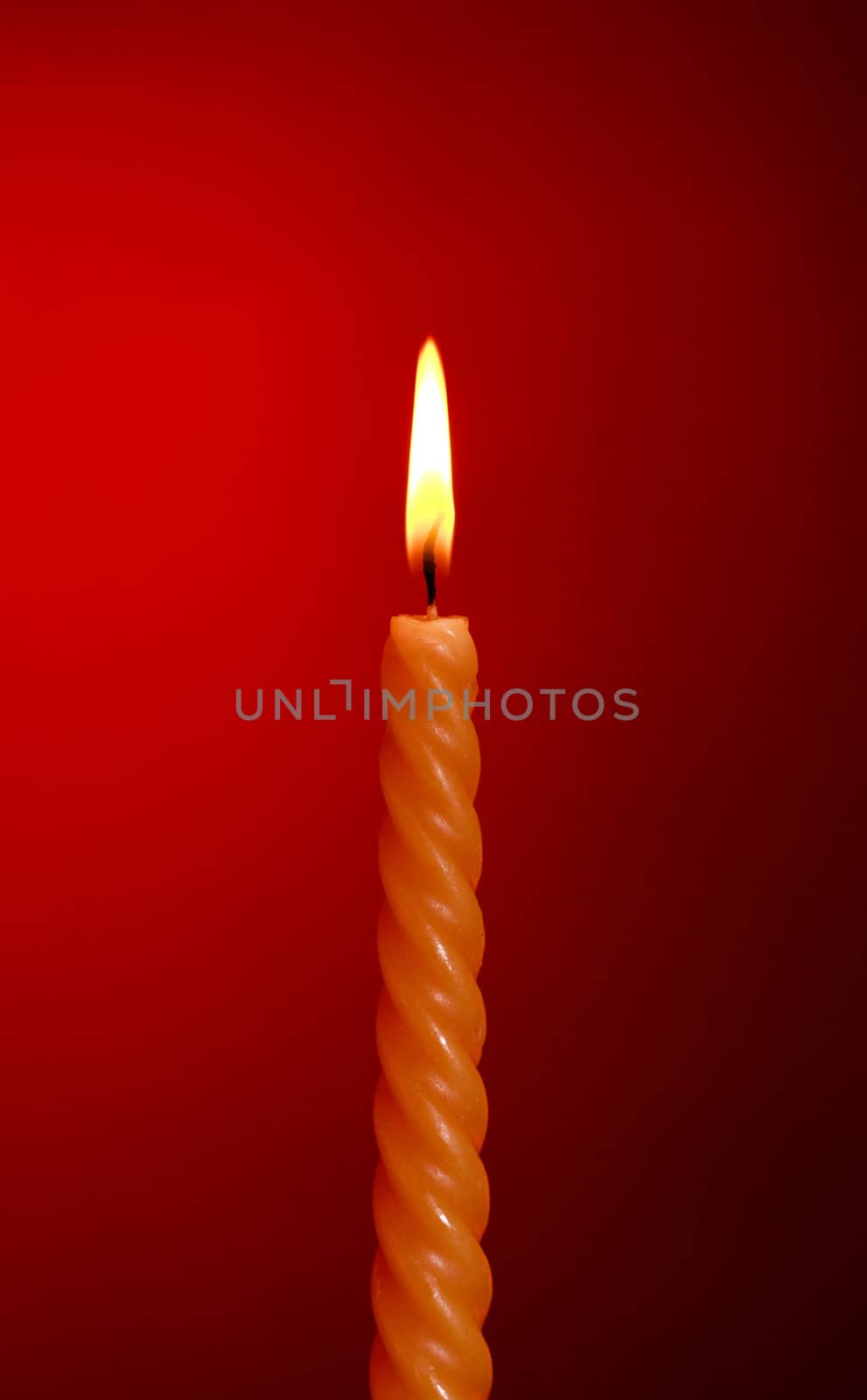 one twisted burning candle over red background