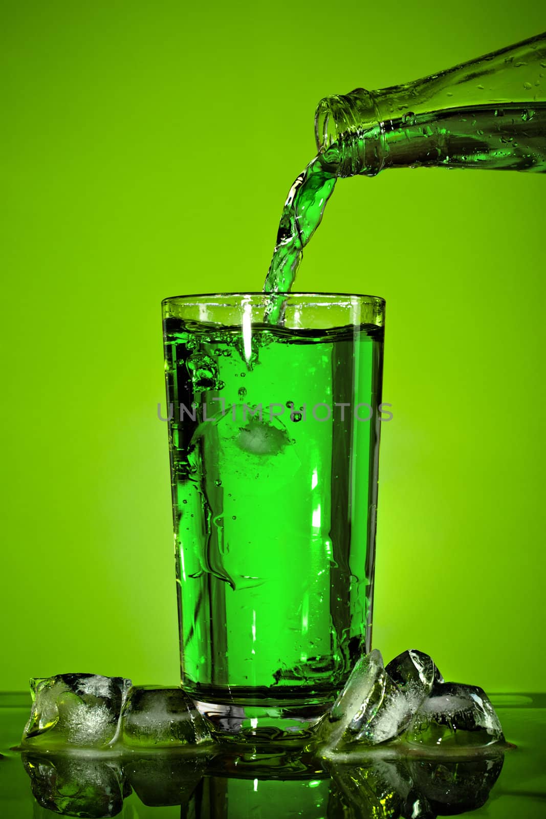 pouring soda in glass over green background