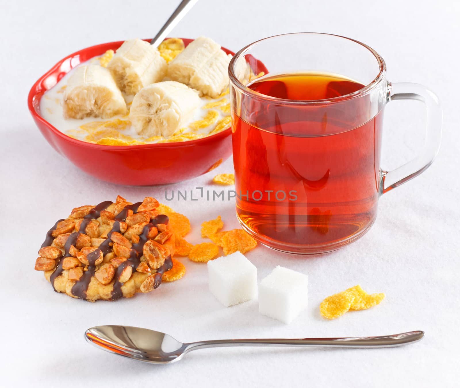 cornflakes with banana in bowl and tea with cookie