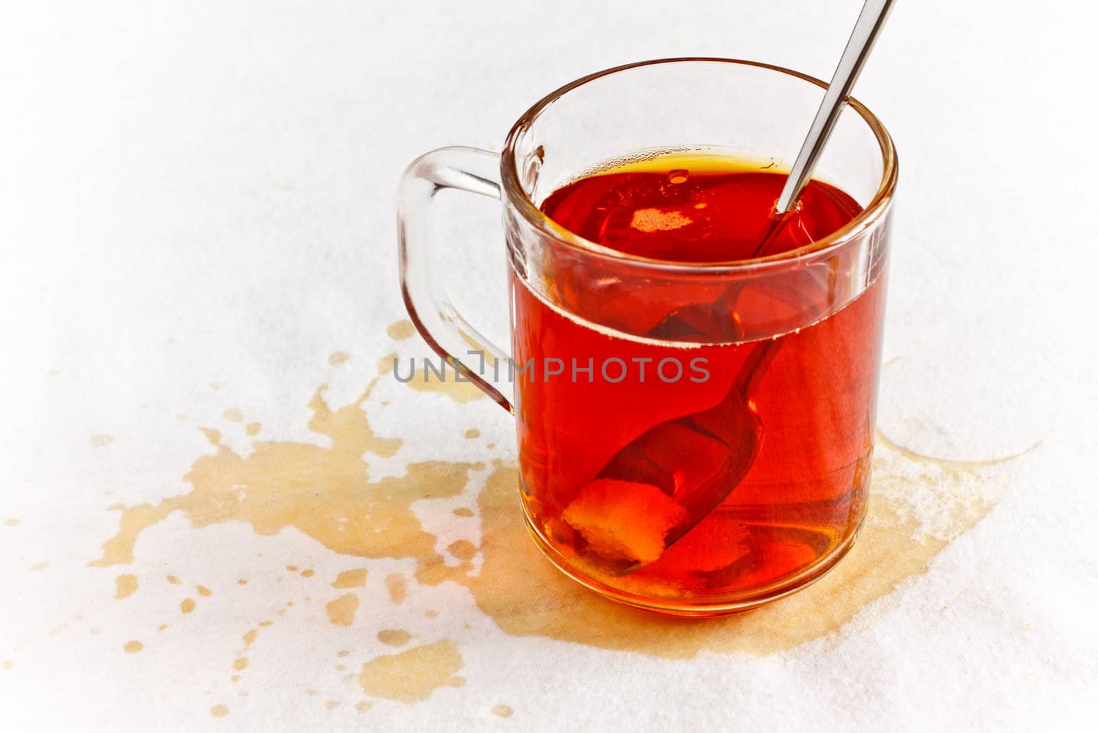 tea in glass spilled on table with white napkin