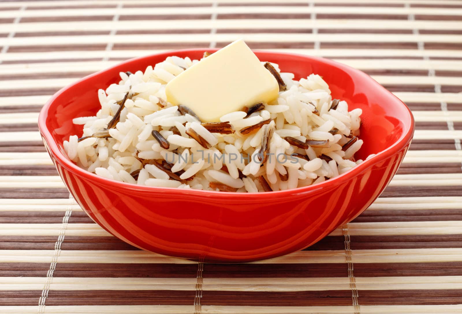 red bowl with cooked rice and butter on bamboo napkin