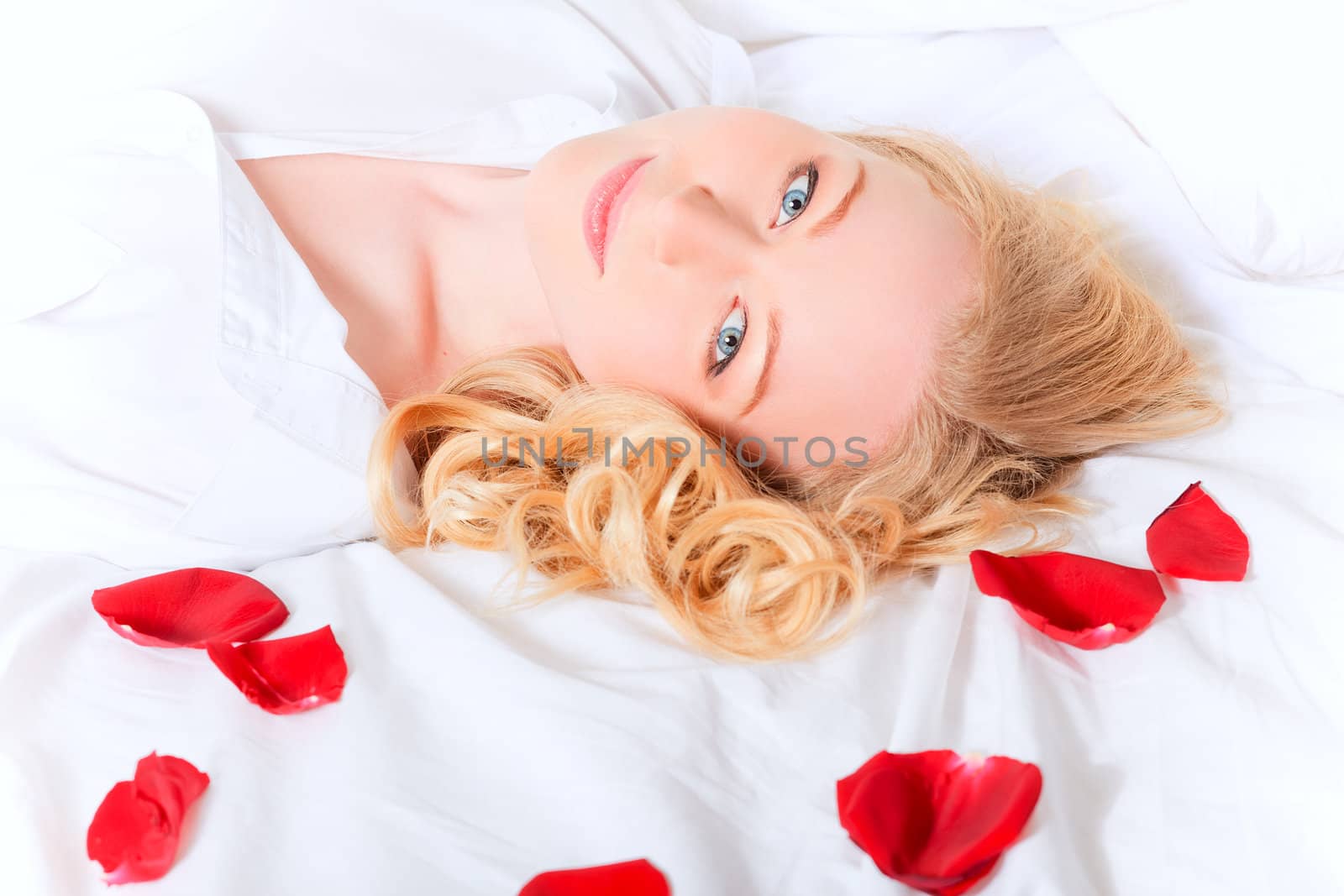 portrait of pretty woman laying in bed with rose petals