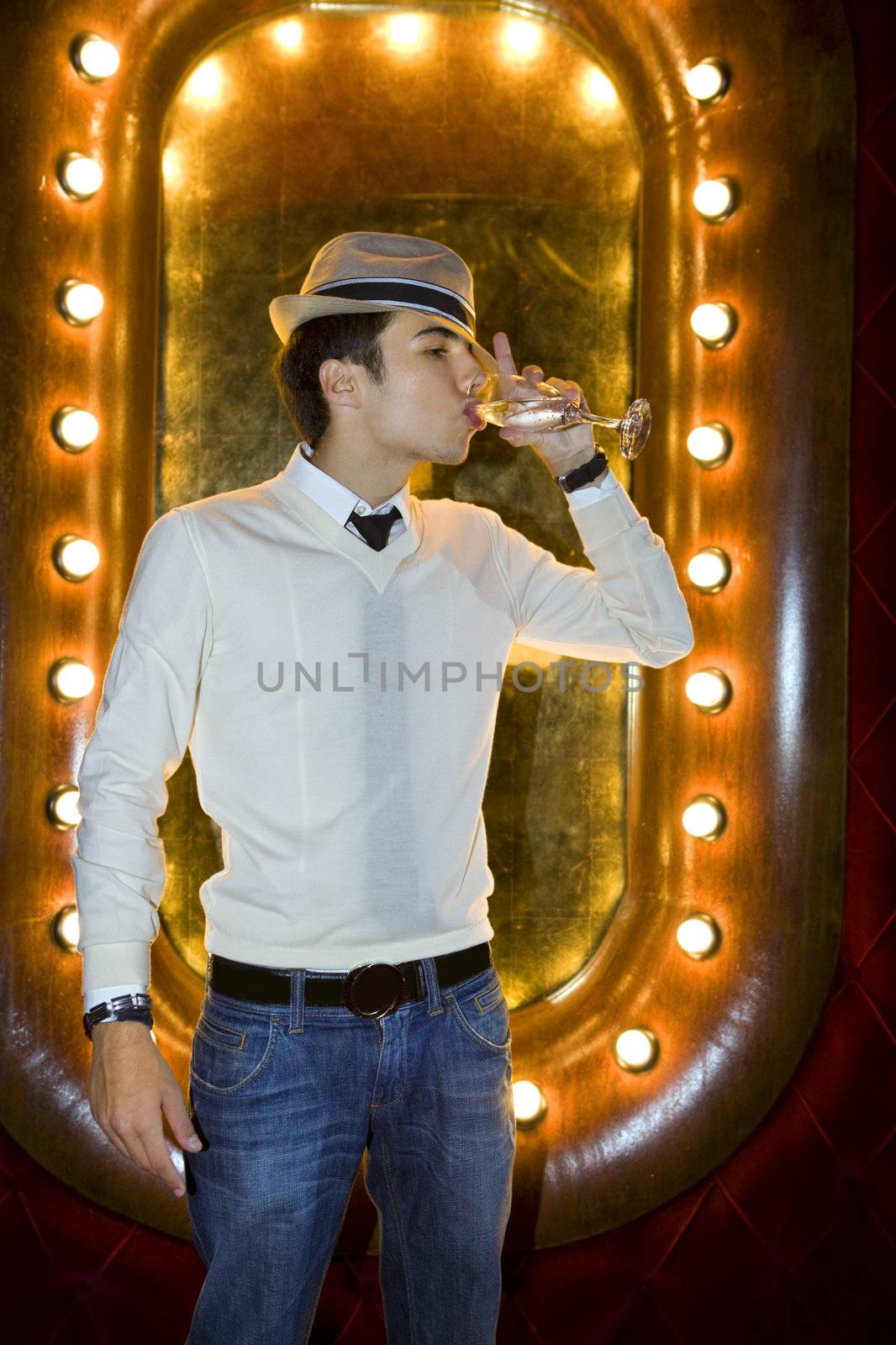 Man with hat in night club, with a glass of wine on the hand