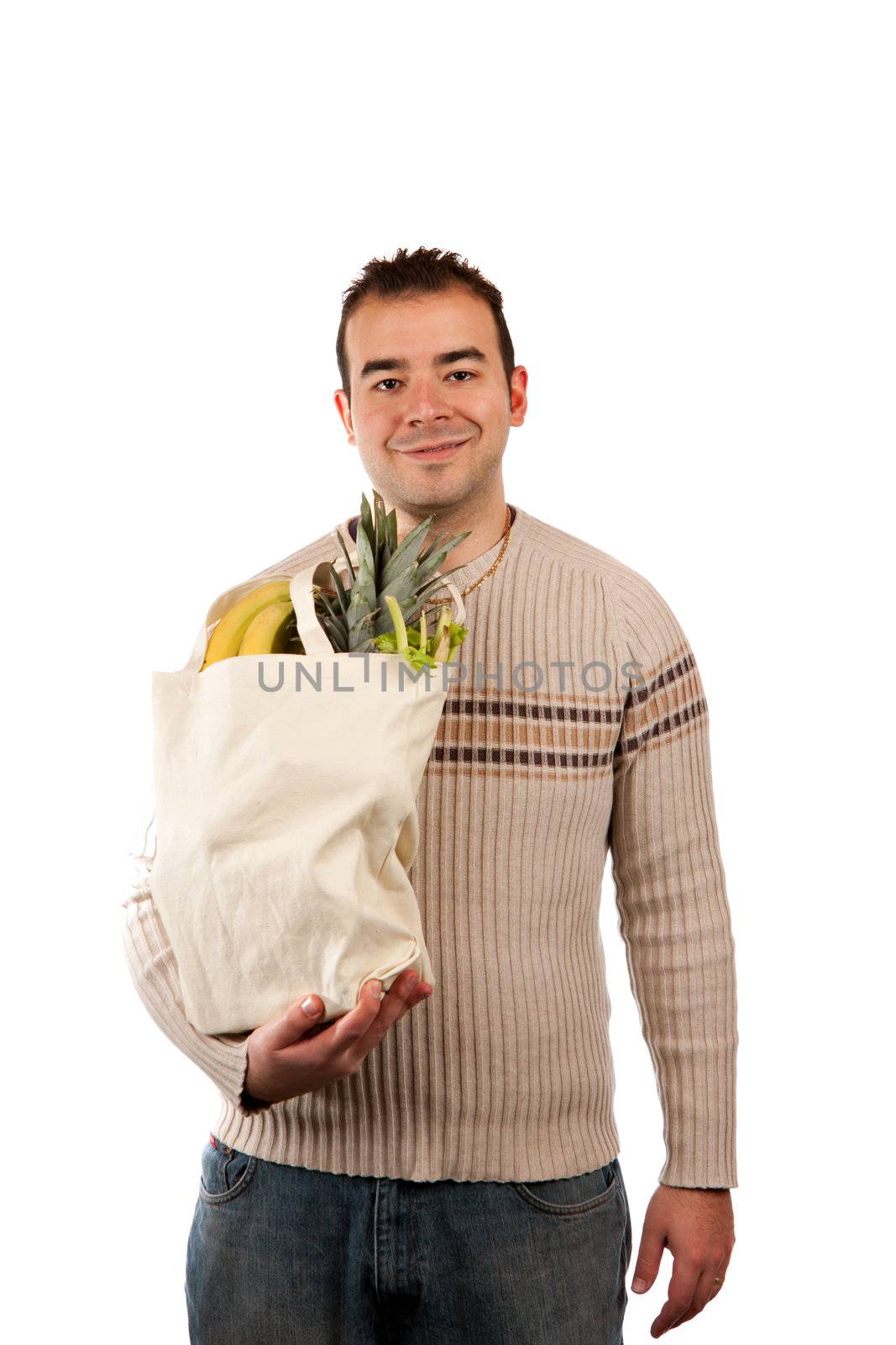 White male grocery shopper smiling while holding a canvas bag full of fresh food items.