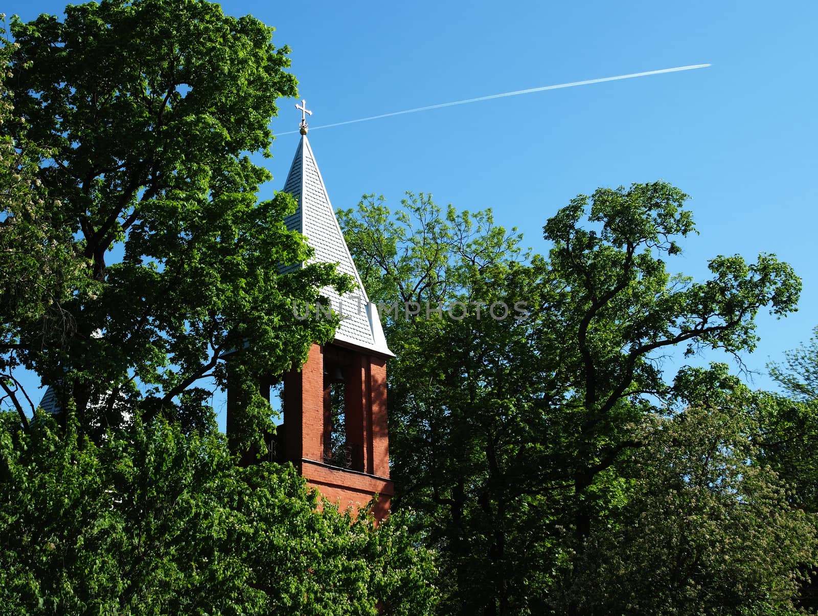 Bell tower with golden cross on blue sky background