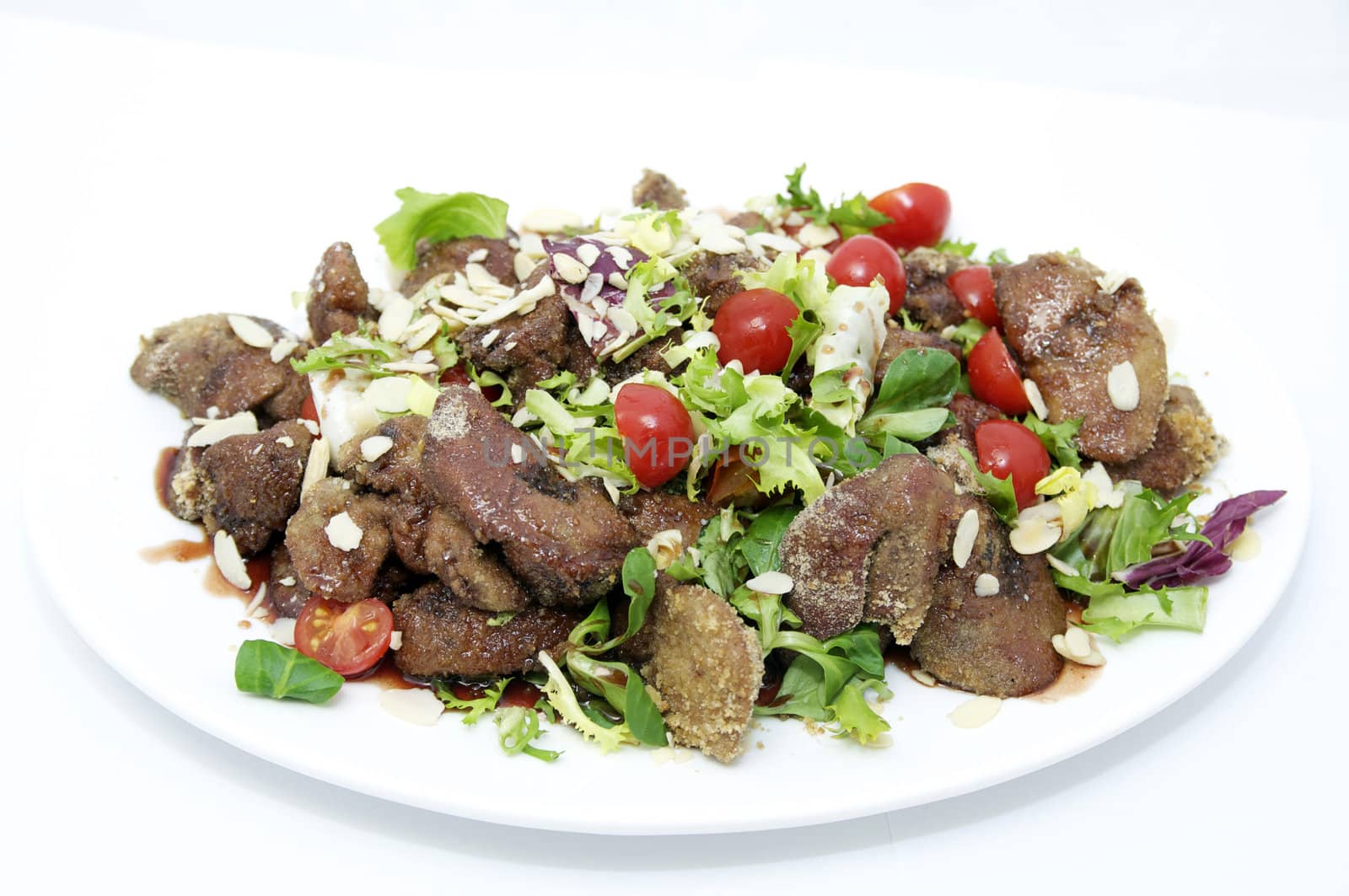 fried liver with vegetables on a plate on a white background