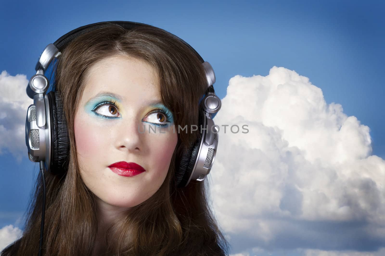 Beautiful Girl listening music over clouds background