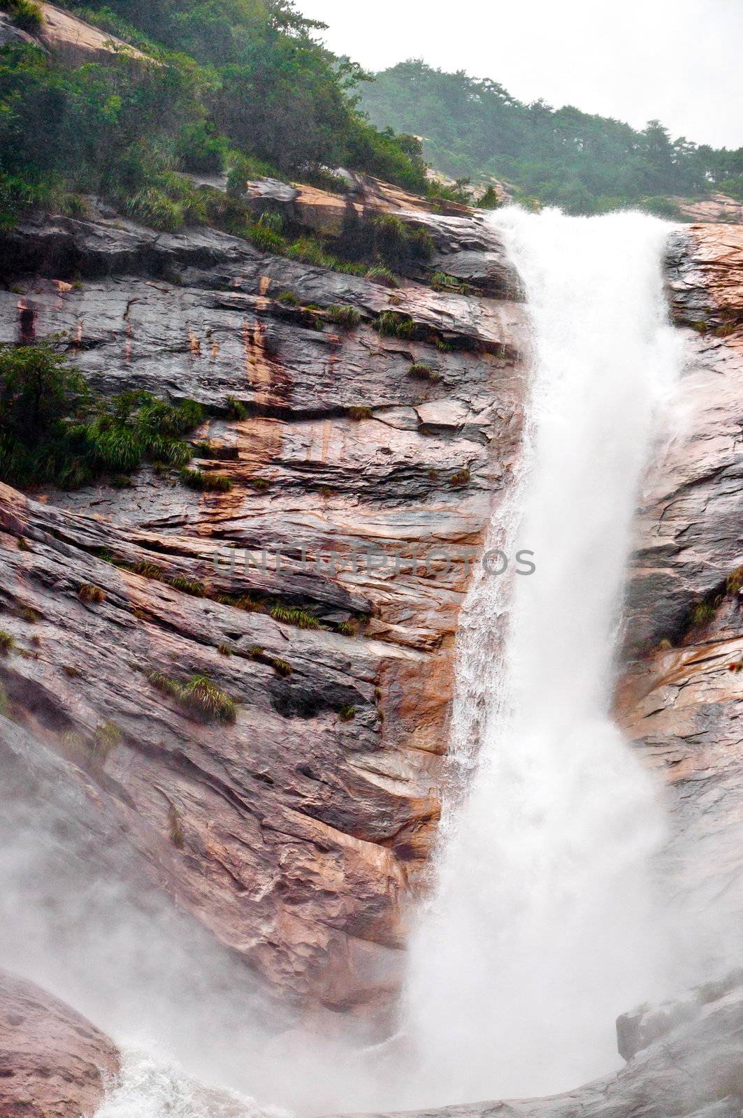 Rocky streaming waterfall in motion on a steep mountain