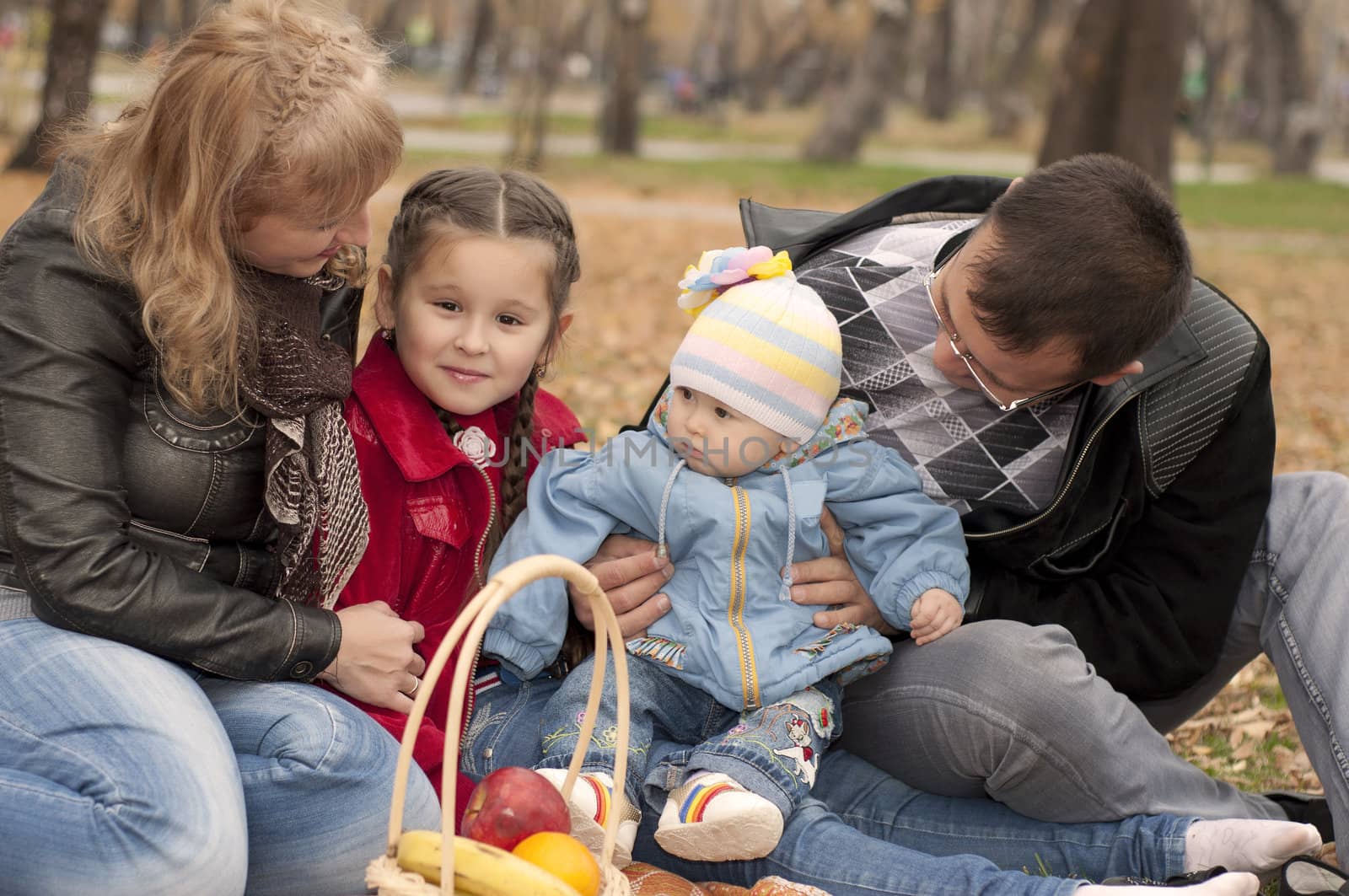 The young family in park, sits on a ground and happy