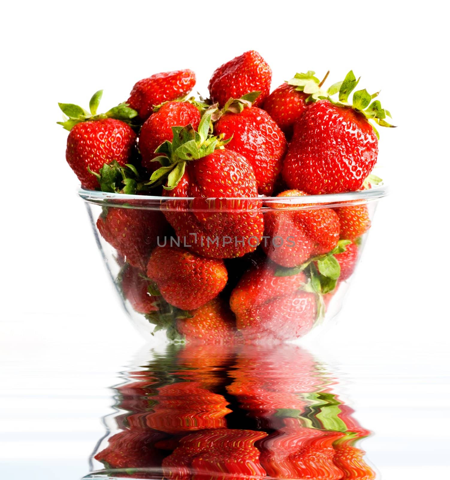 Red fresh strawberries in a glass. Reflection in water