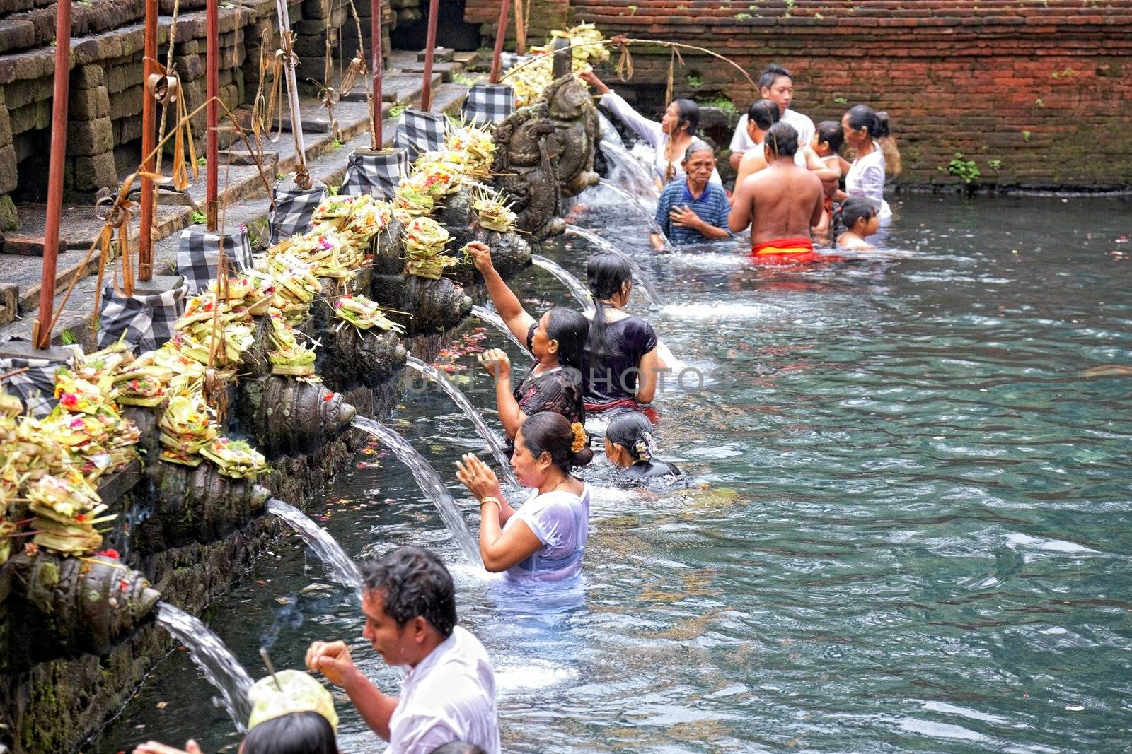 TAMPAK SIRING, BALI, INDONESIA - OCTOBER 30: People praying at holy spring water temple Puru Tirtha Empul during purification ceremony on October 30, 2011 in Tampak Siring, Bali, Indonesia