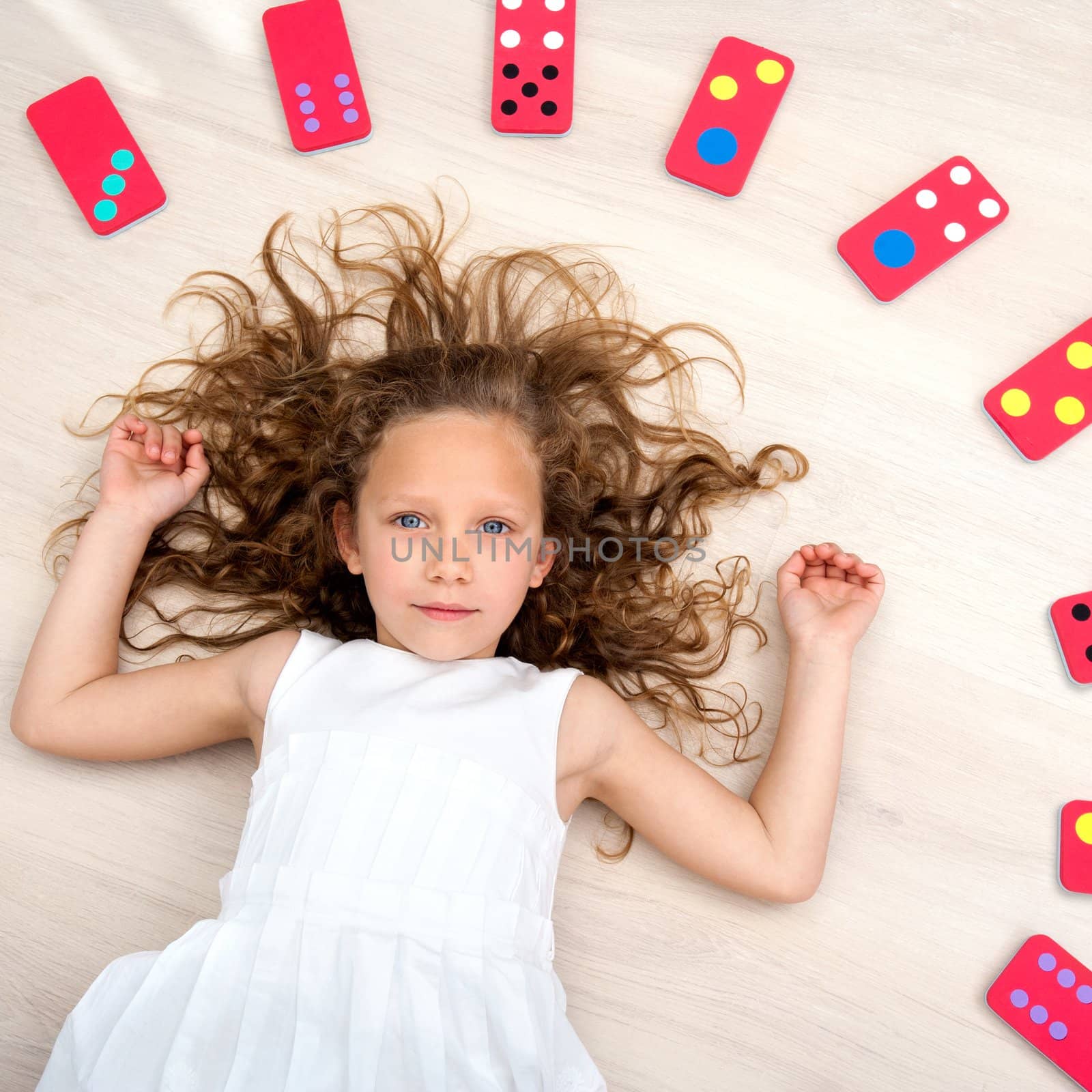 Young girl on floor with domino pieces by karelnoppe